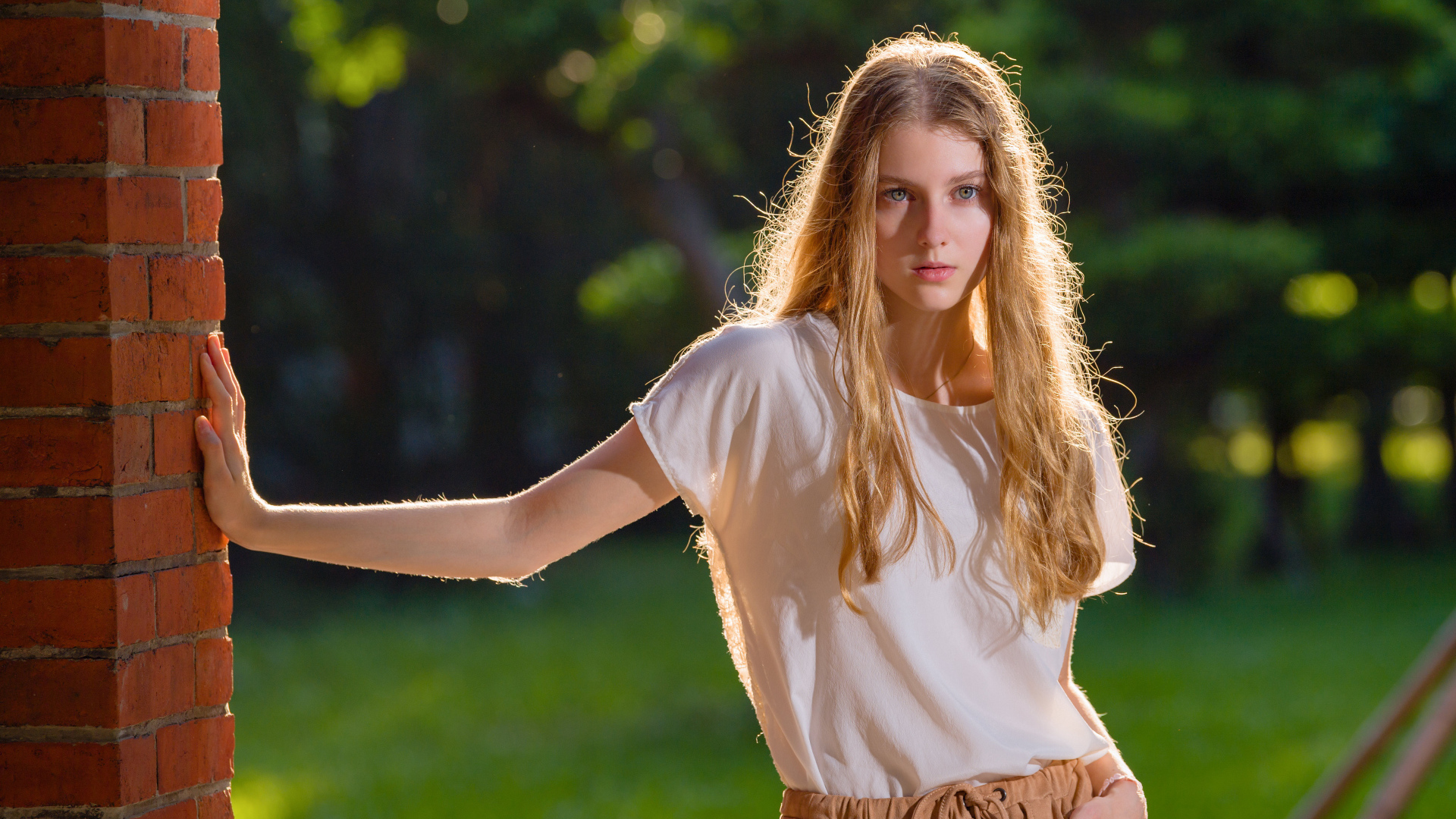 Красивая нежная девушка стоит у стены 