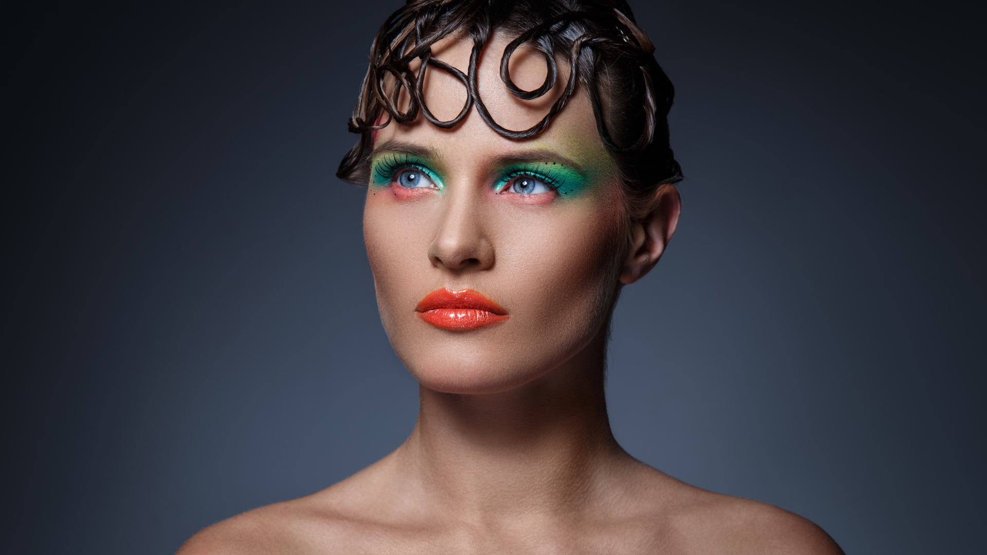 Девушка с ярким макияжем на сером фоне 