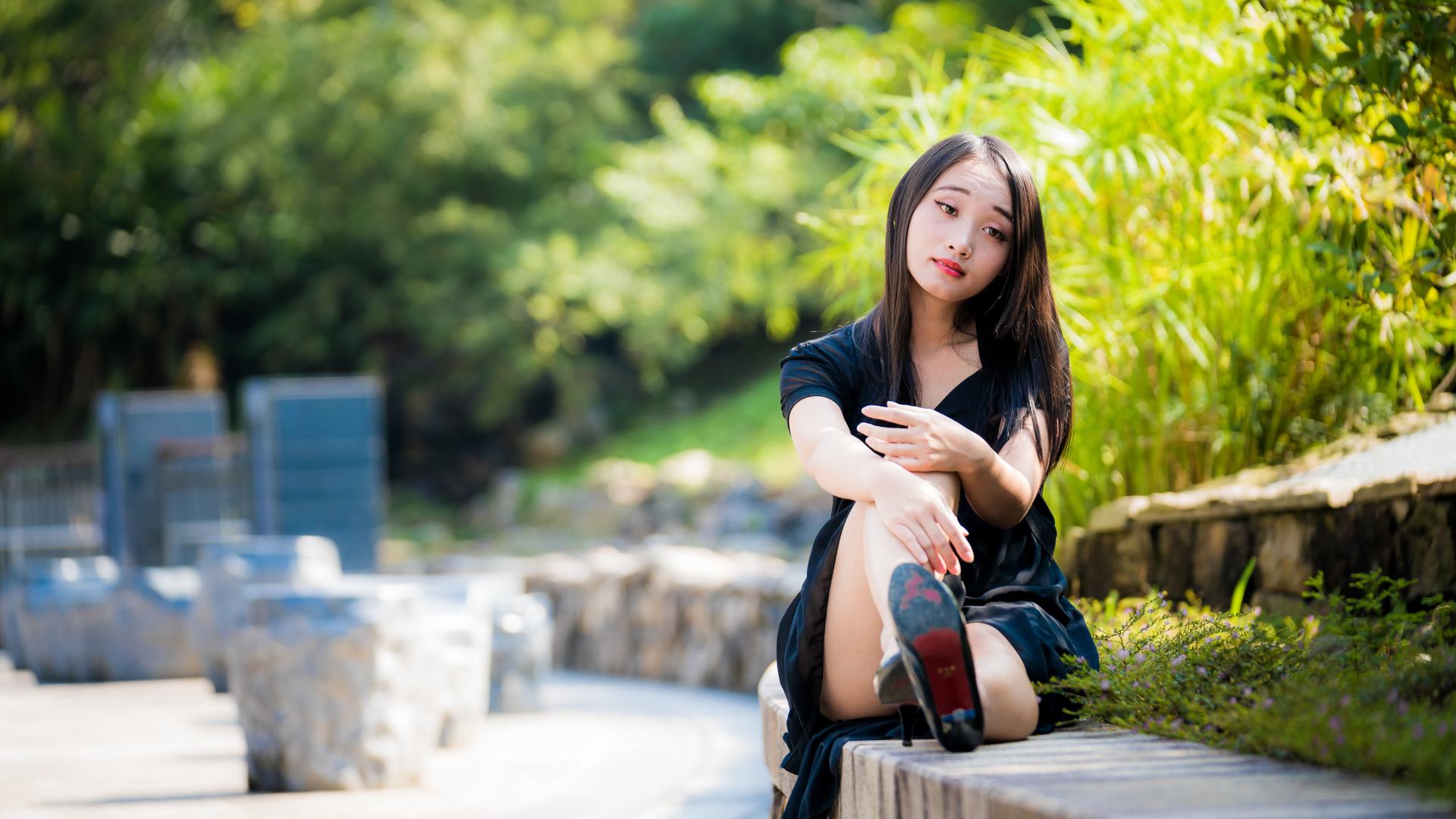 Грустная девушка в черном платье отдыхает в парке