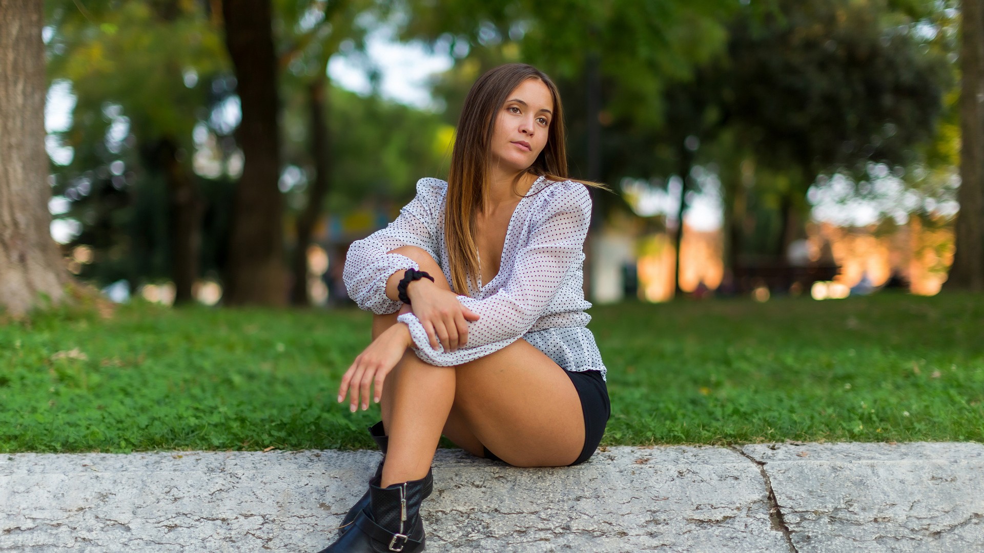 Грустная девушка сидит на земле в парке 