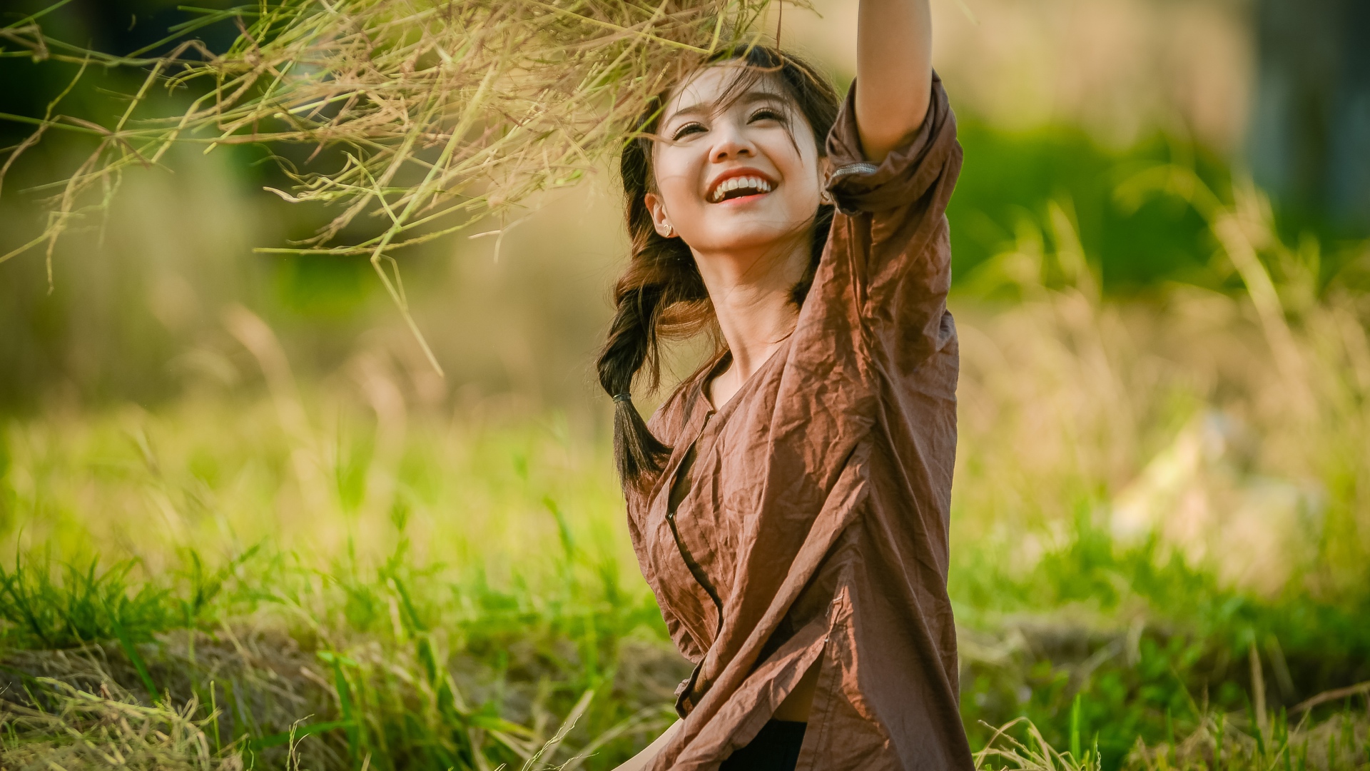 Улыбающаяся девушка азиатка с травой в руках 