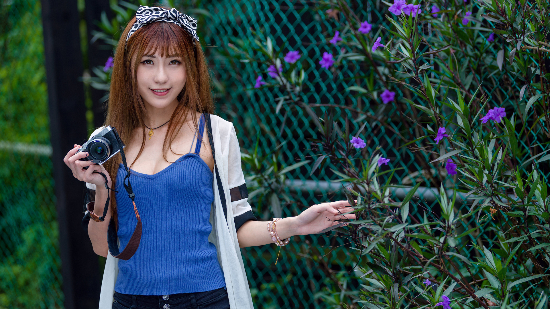 Улыбающаяся девушка фотограф стоит у сетки 