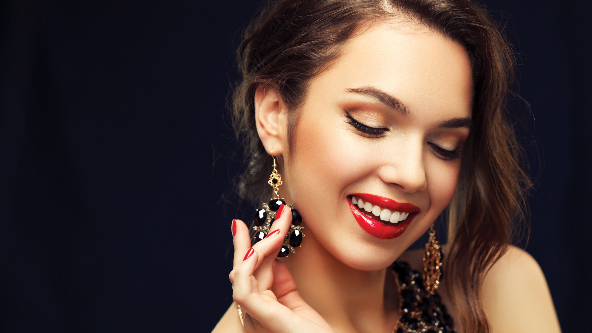 Улыбающаяся девушка носит украшения с черными камнями
