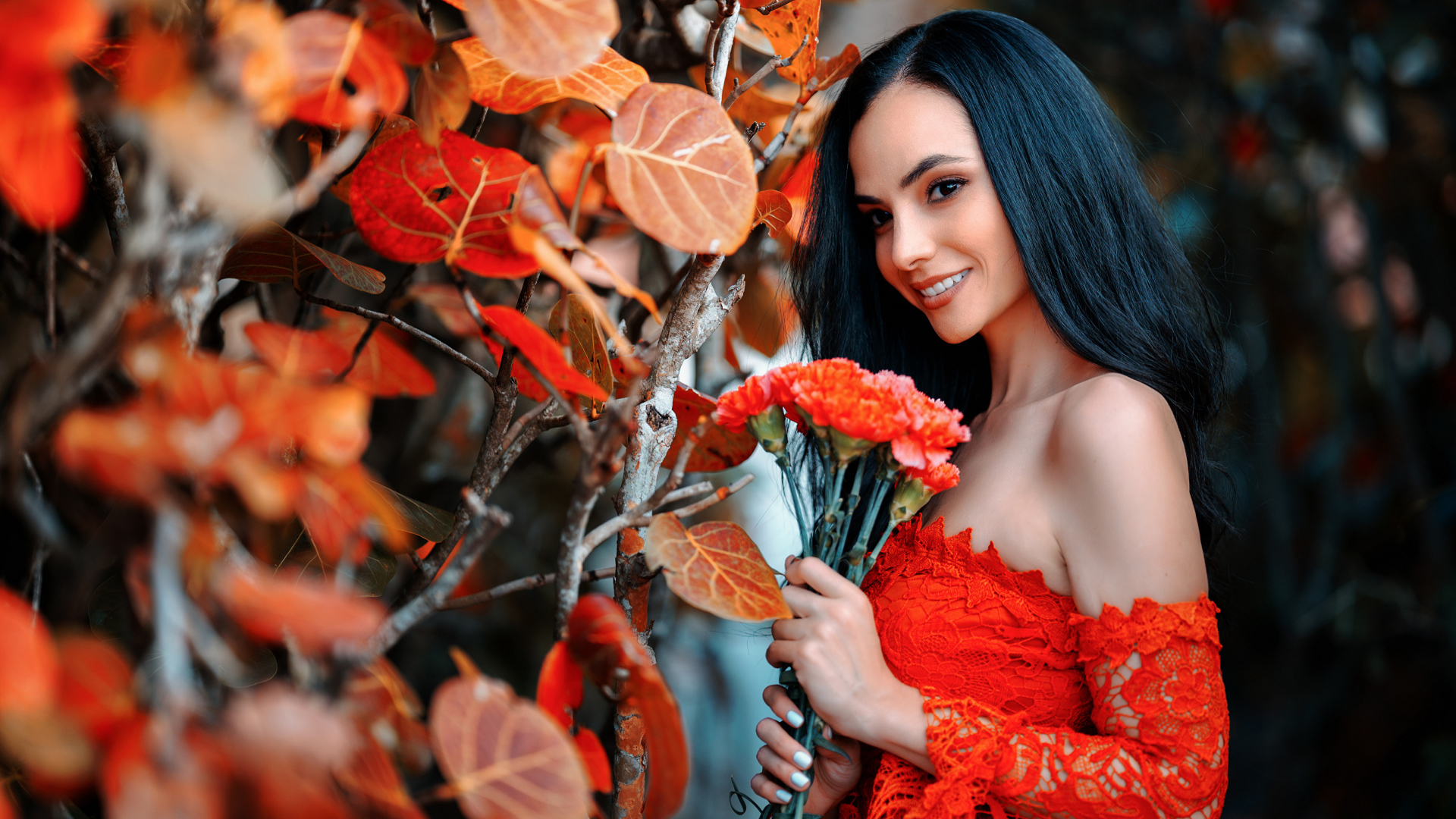 Улыбающаяся девушка с букетом гвоздик у стены с осенними листьями