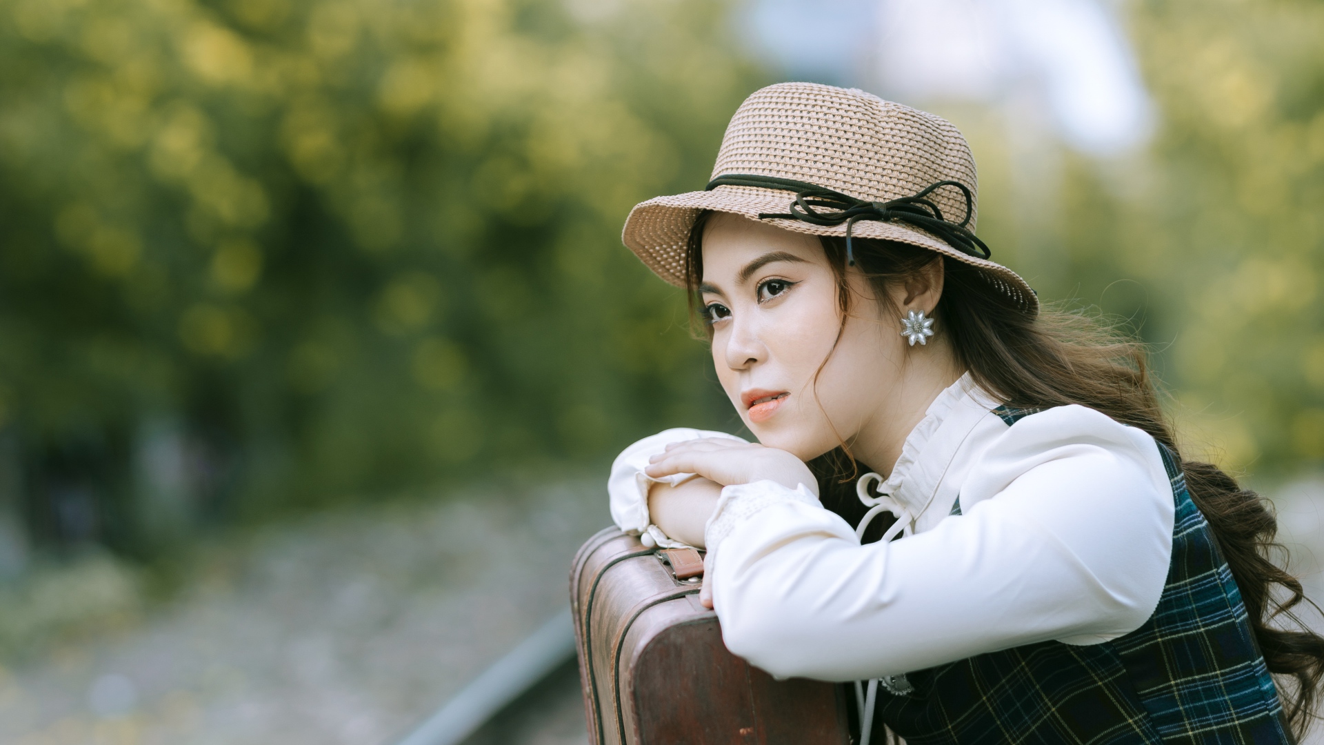 Молодая азиатка в шляпе с чемоданом