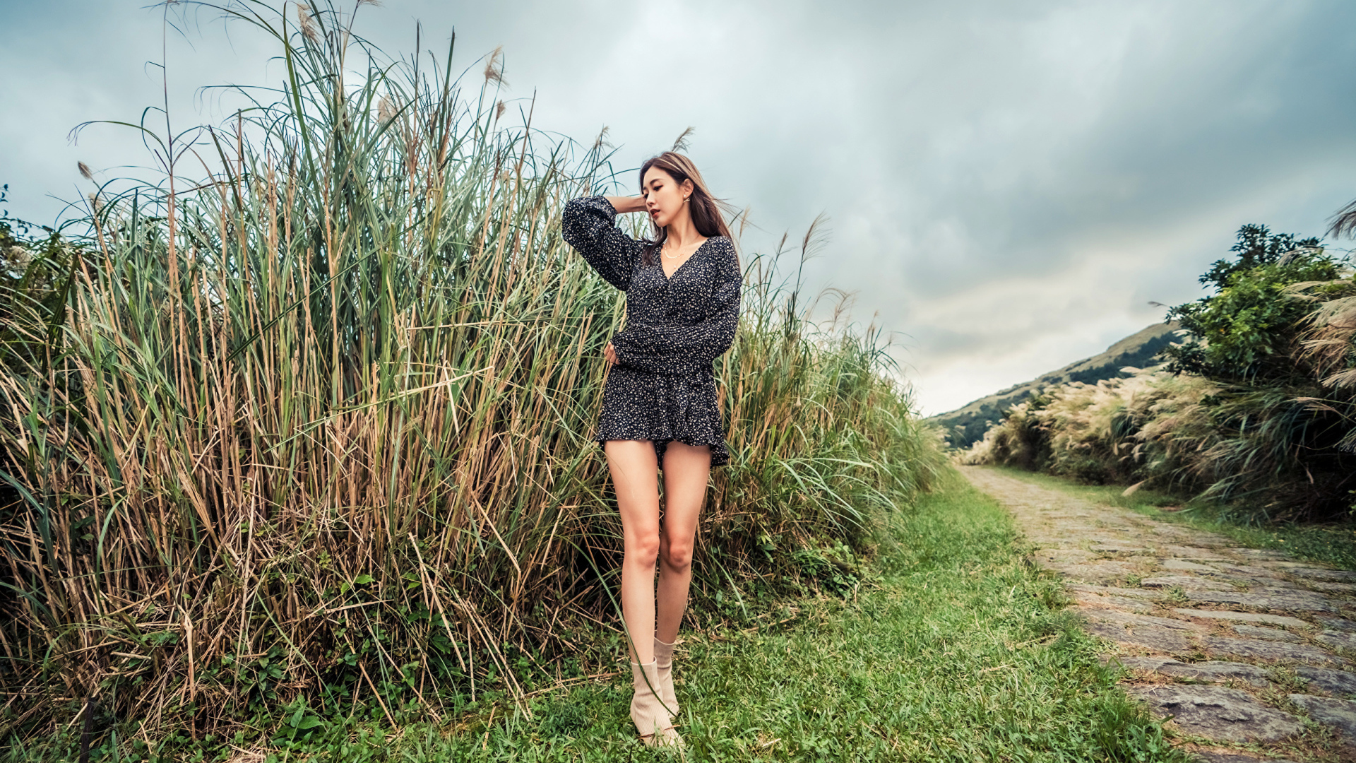Молодая девушка азиатка стоит у зеленой травы
