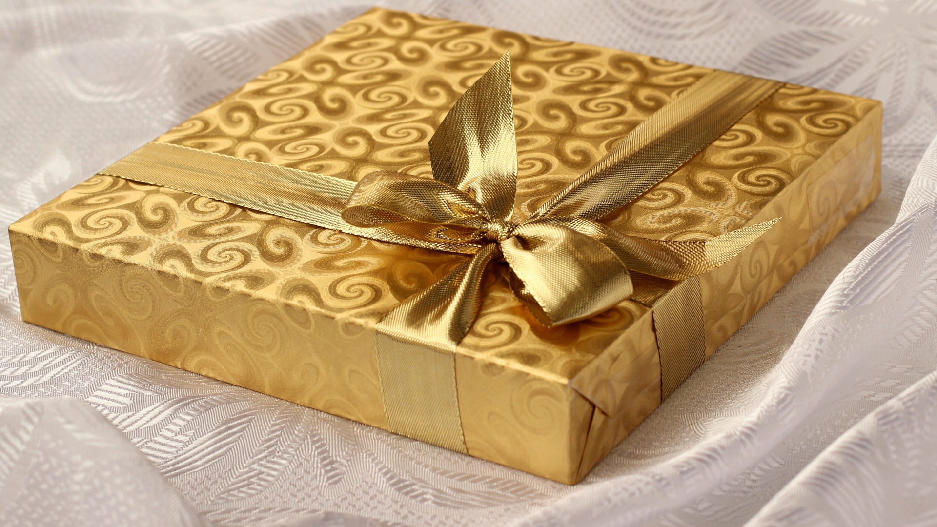 Beautiful golden box with a gift on the bed