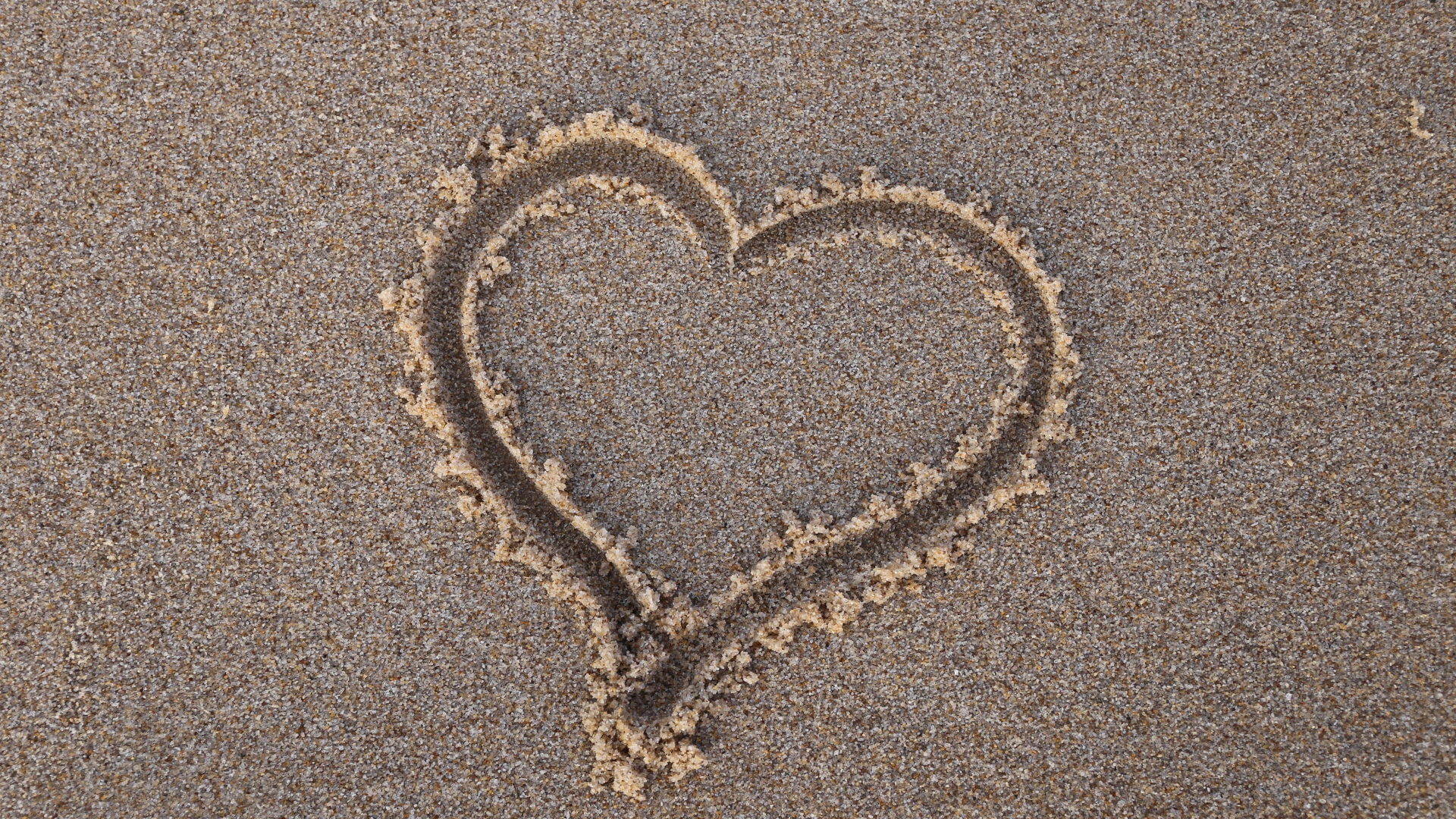 Сердце нарисовано на мокром песке 