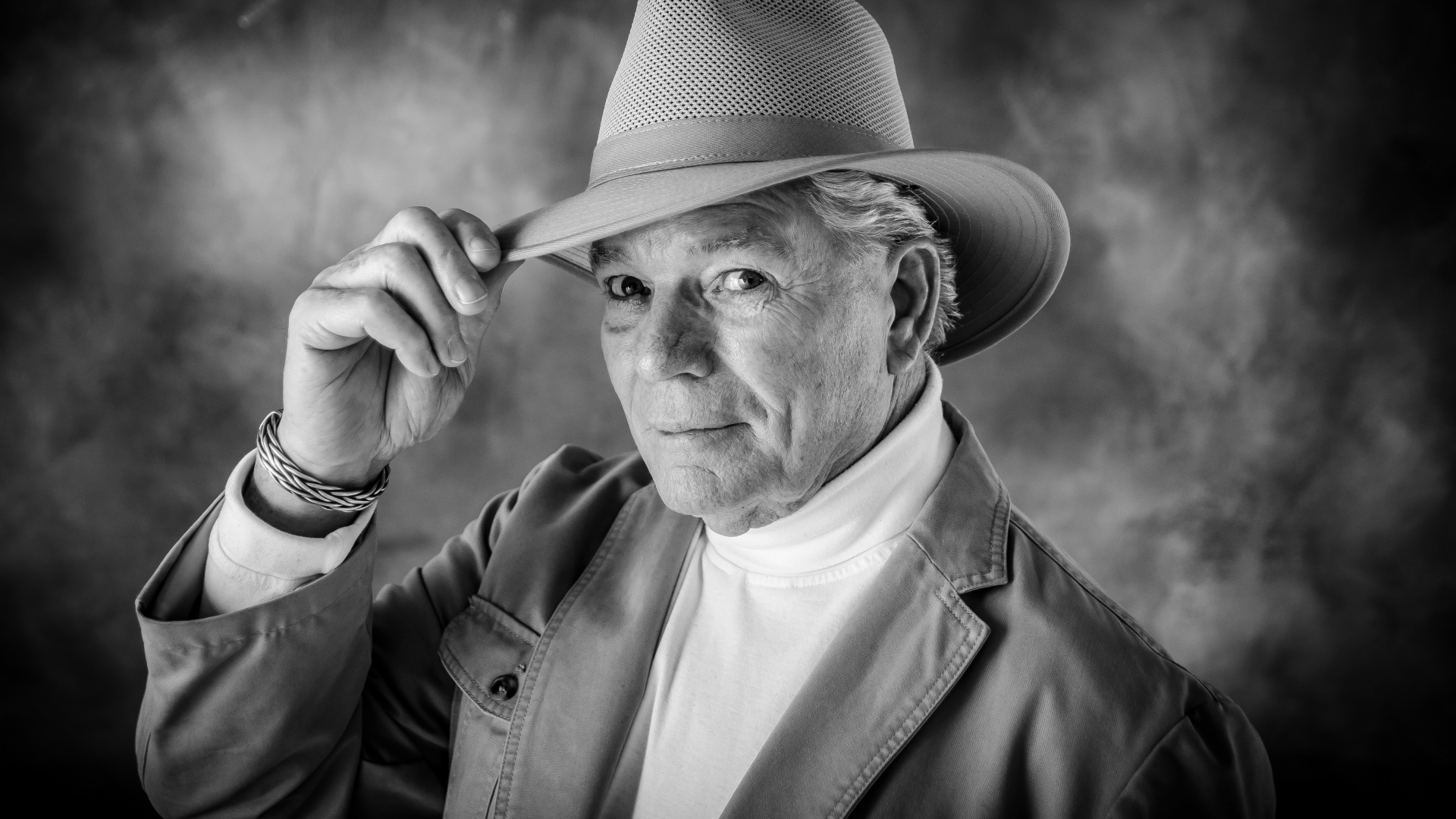 Пожилой мужчина в шляпе на фоне дыма 