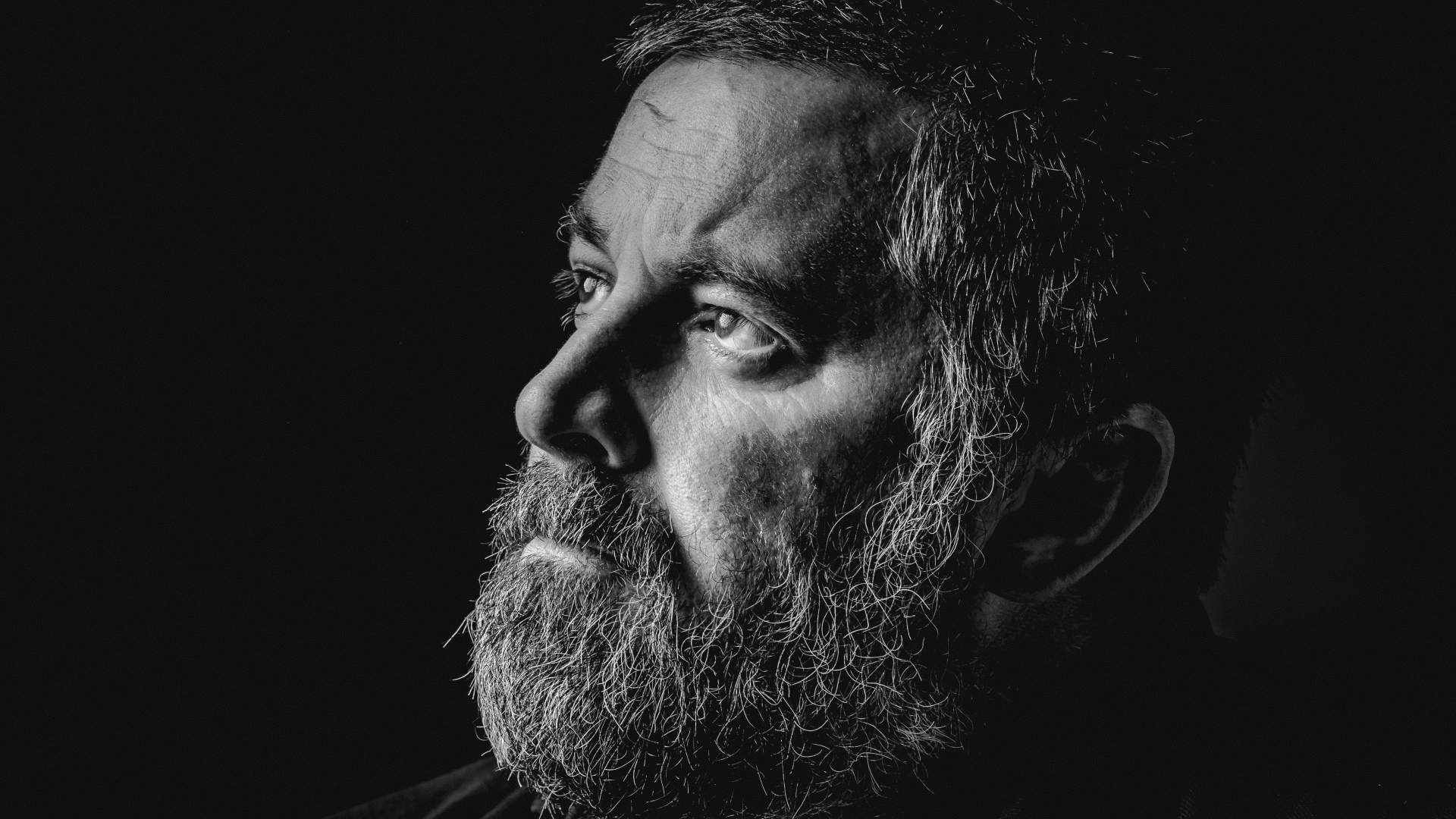 Мужчина с седой бородой на черном фоне 