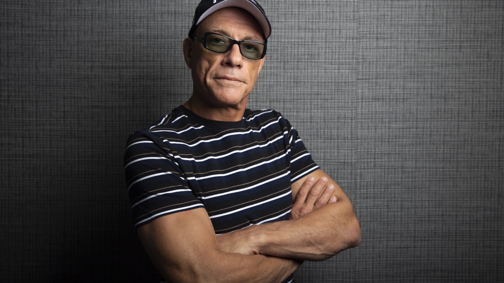 Популярный актер Жан-Клод Ван Дамм в кепке у стены