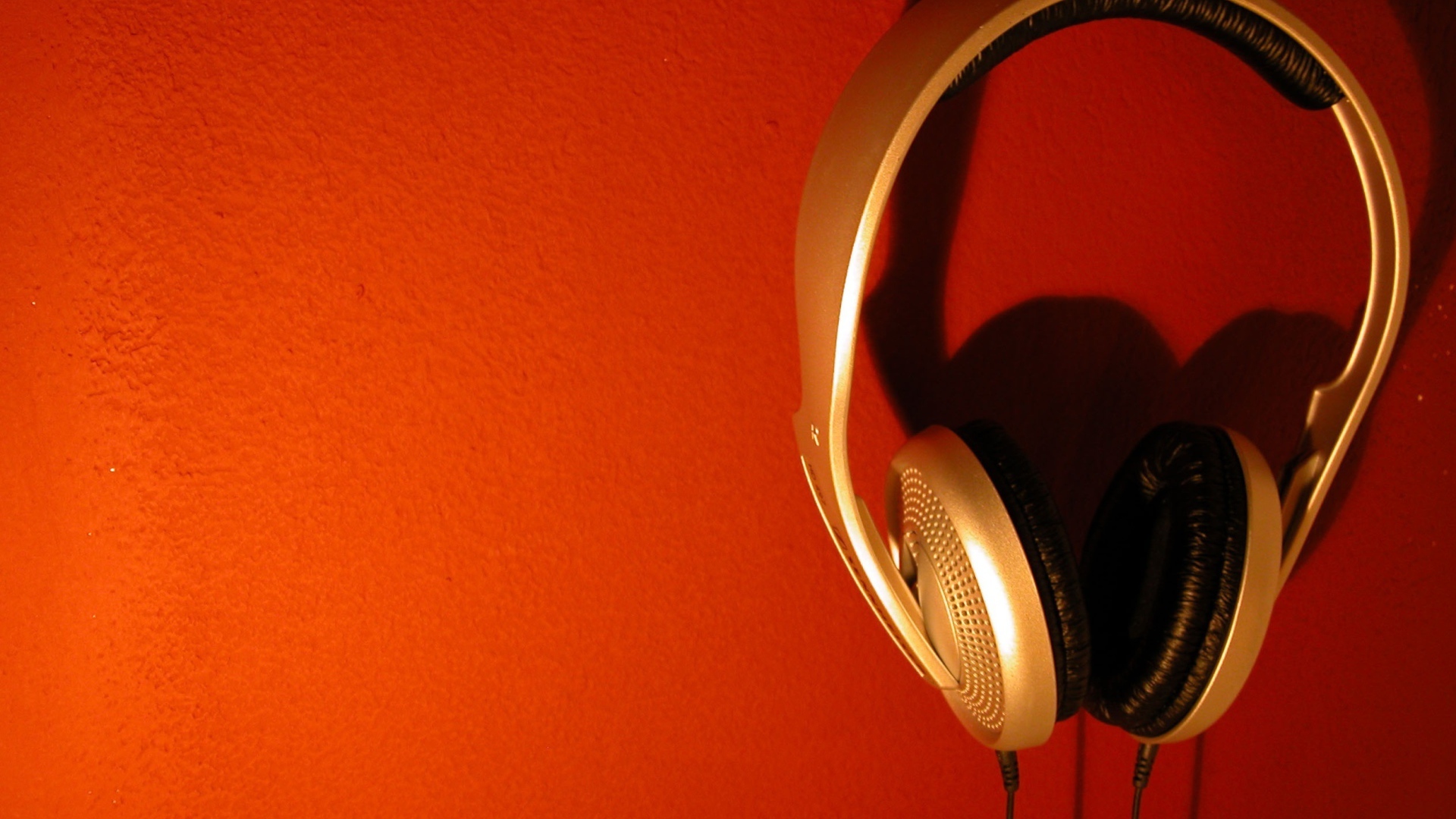 Большие золотые наушники на оранжевом фоне 