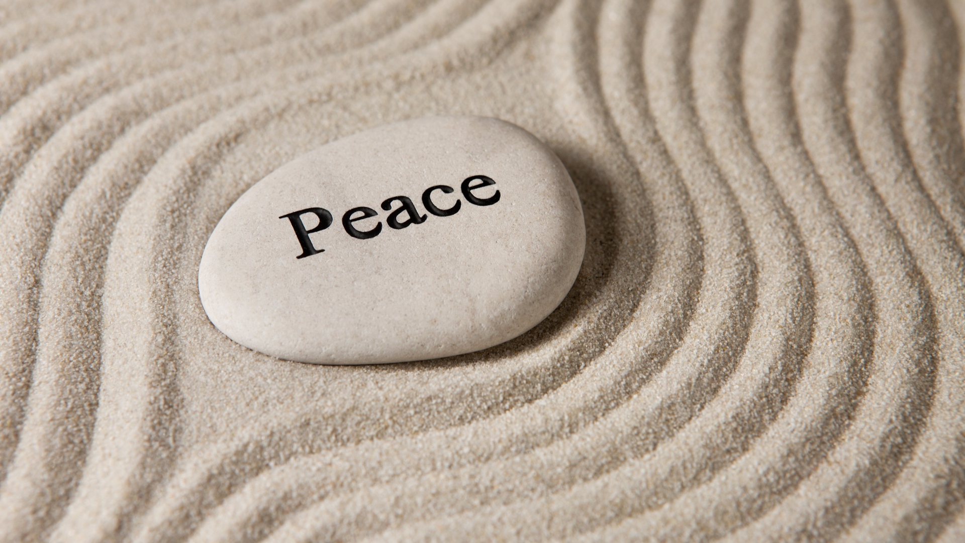 Белый камень с надписью на песке с волнами