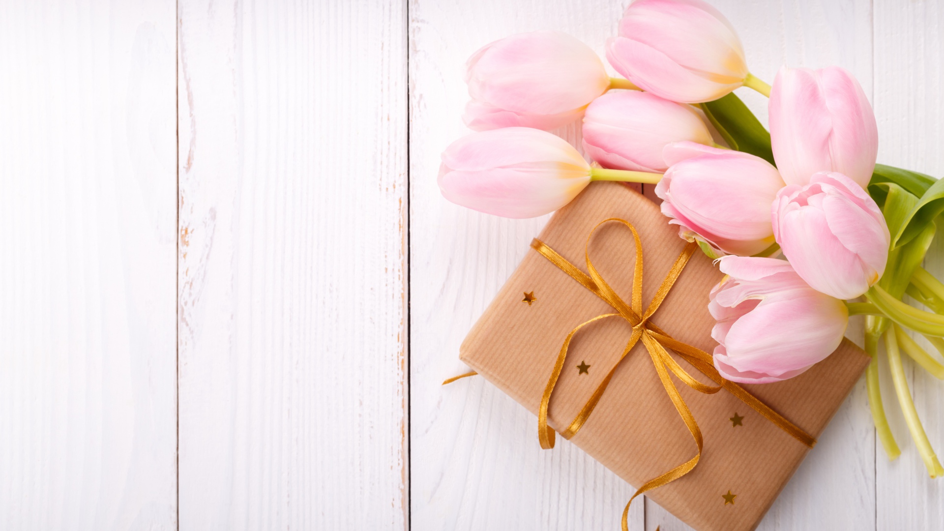 Букет нежных тюльпанов с подарком на деревянном столе