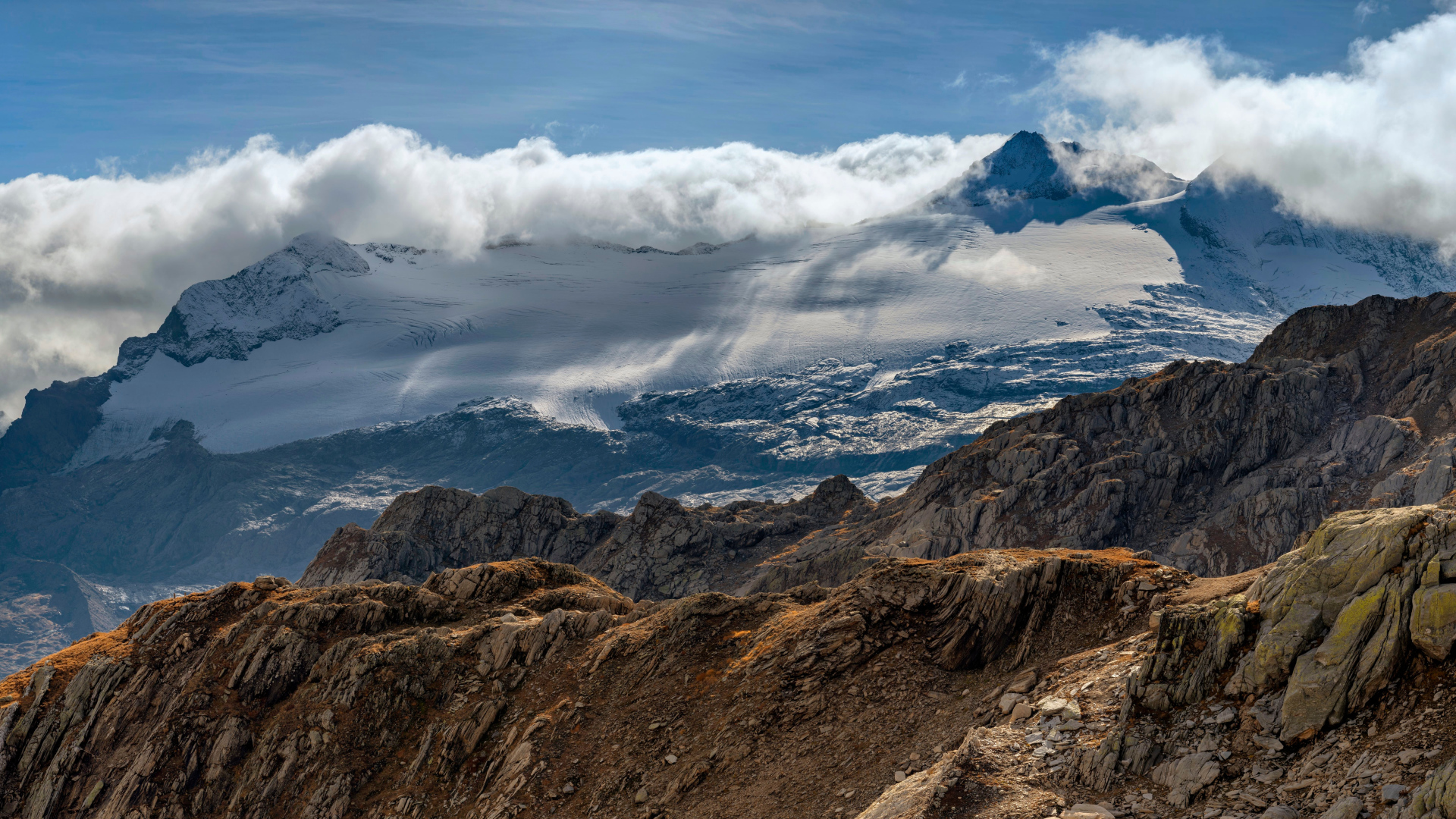 Густые белые облака над заснеженными Альпами
