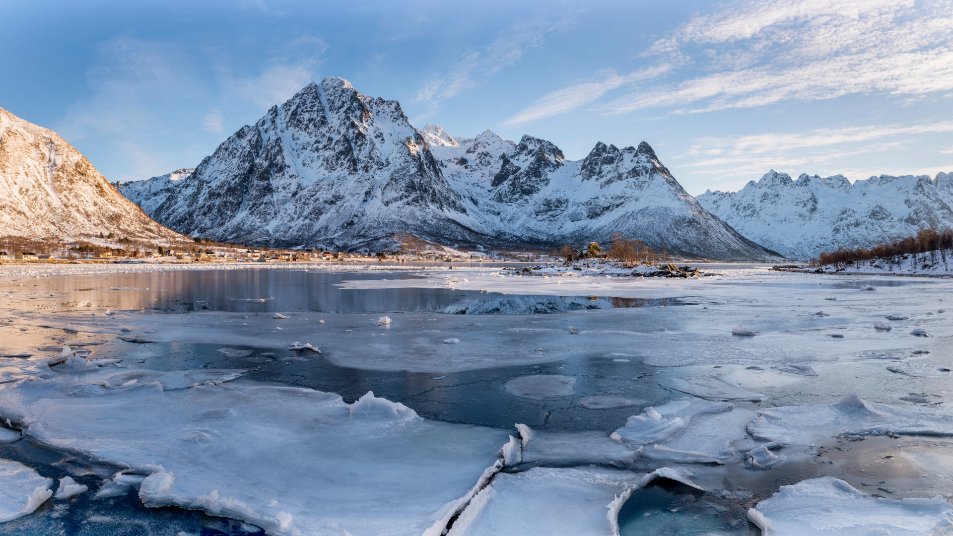 Покрытое льдом озеро у заснеженной горы