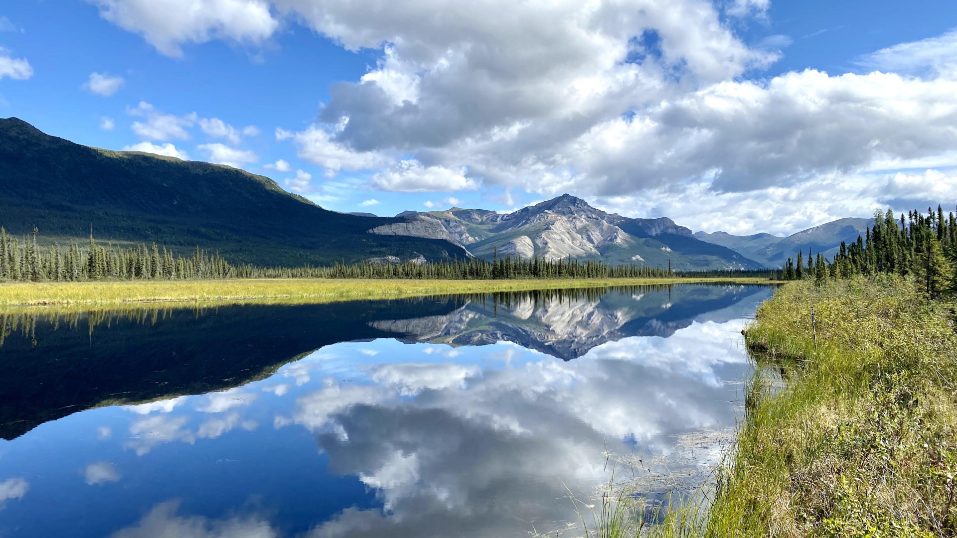 Небо с белыми облаками отражается в реке 