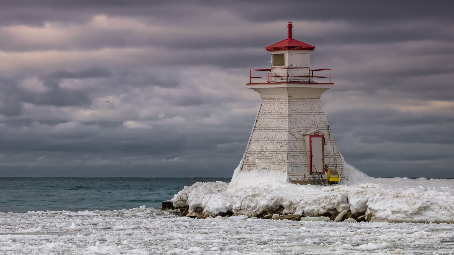 Маяк на покрытом льдом берегу у моря