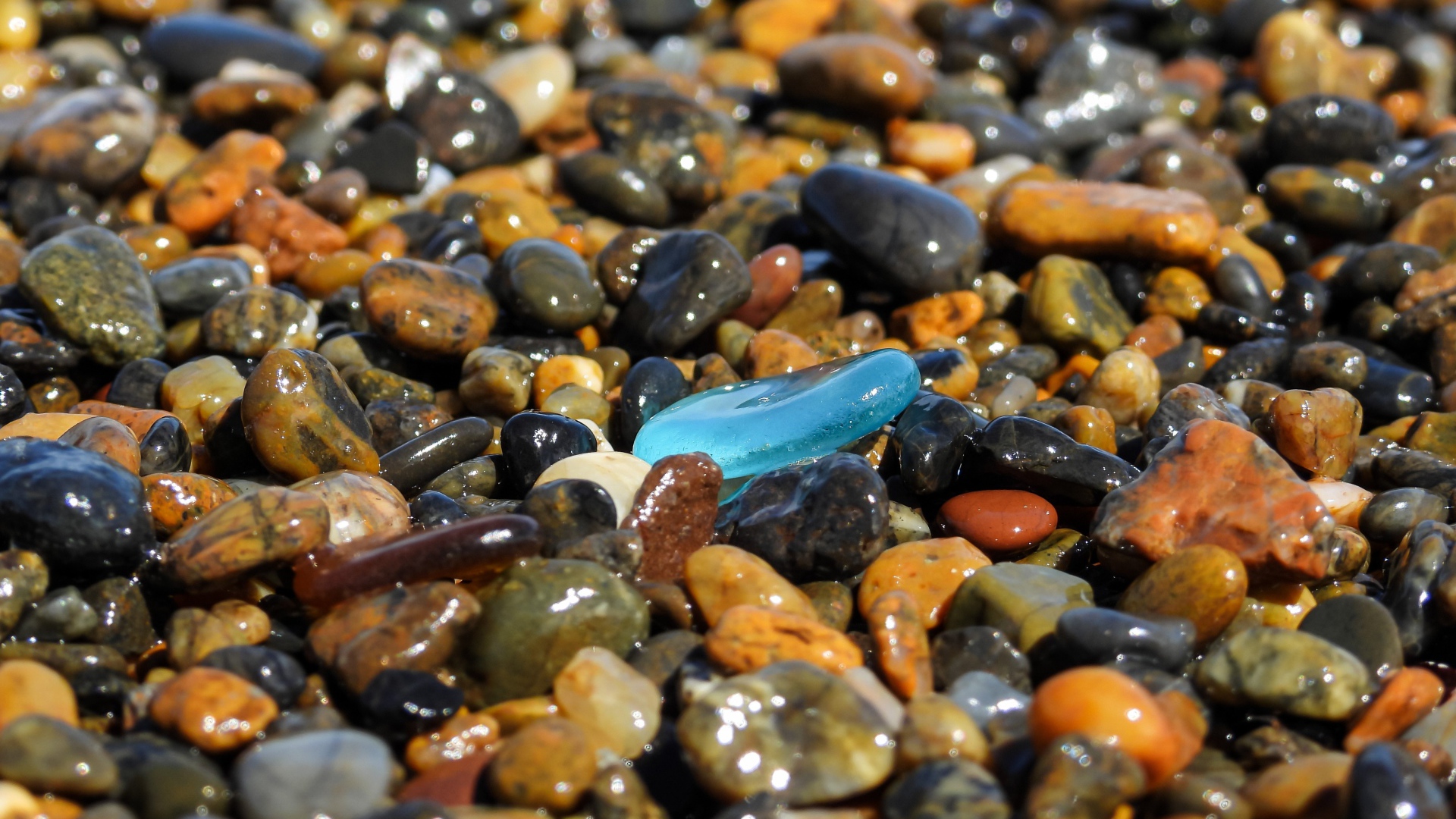 Гладкие разноцветные мелкие камни на пляже 