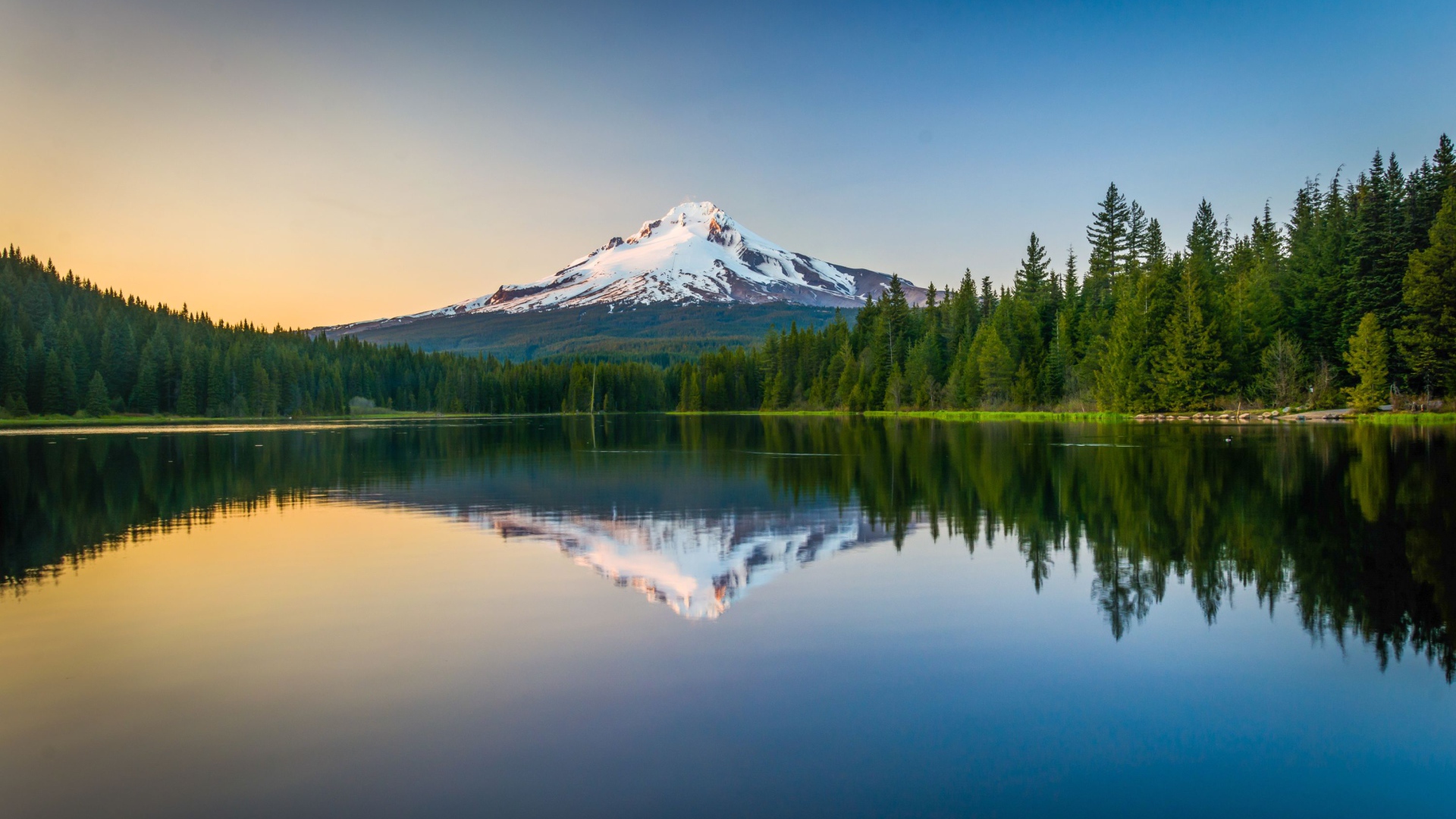 Заснеженная вершина вулкана отражается в холодной воде озера 