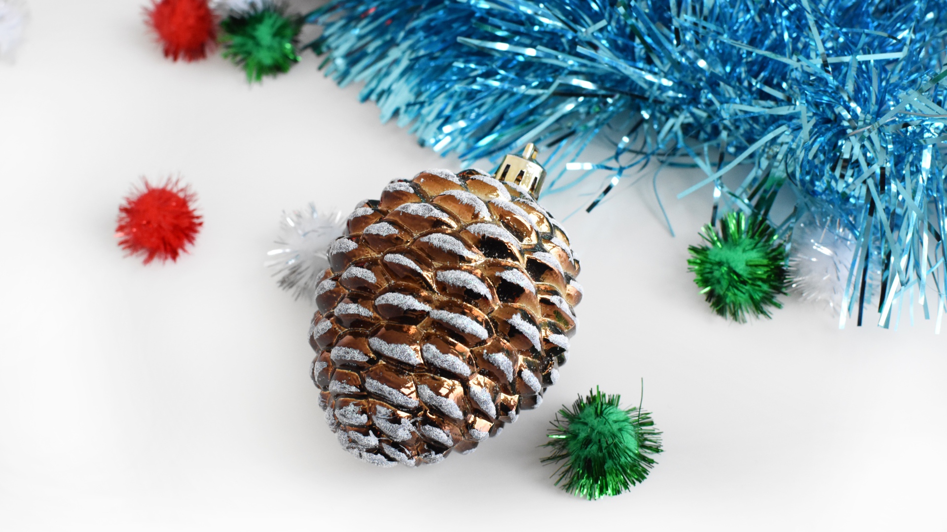 Елочная игрушка шишка с мишурой на белом фоне 