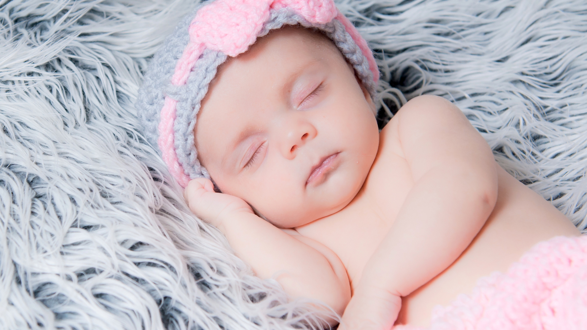 Грудной ребенок спит на меховом одеяле 