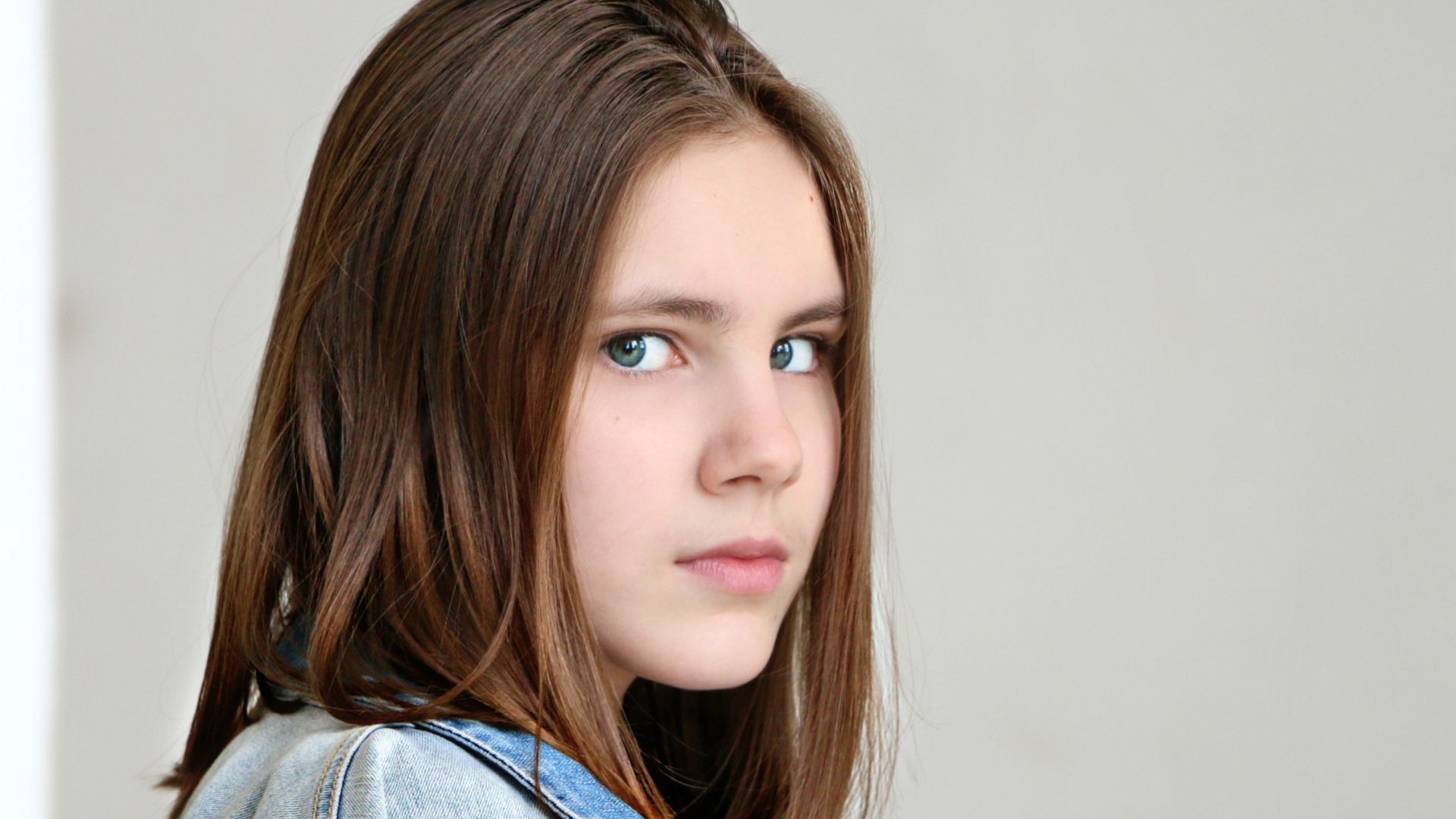 Красивая зеленоглазая девочка на сером фоне