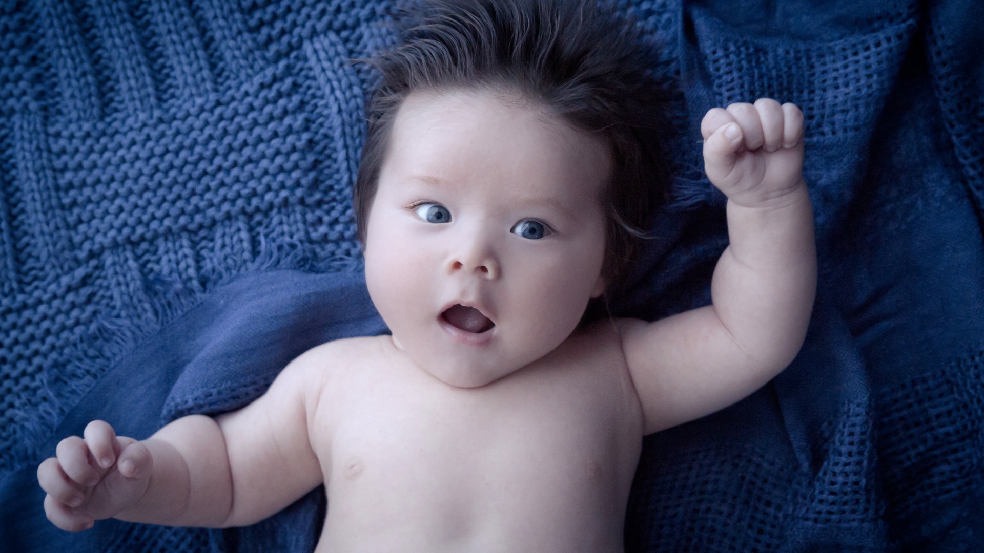 Мальчик с густыми волосами на синем покрывале 