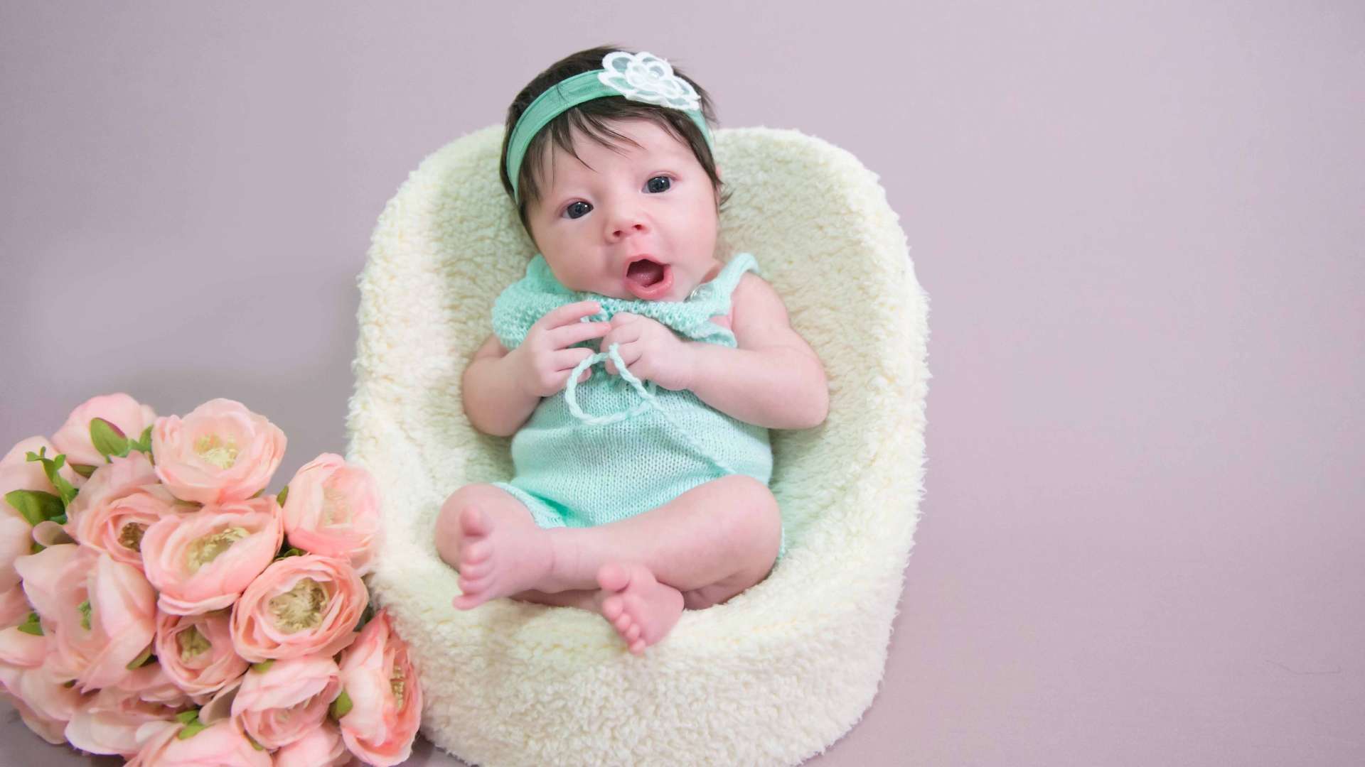 Милая малышка в кресле с букетом цветов