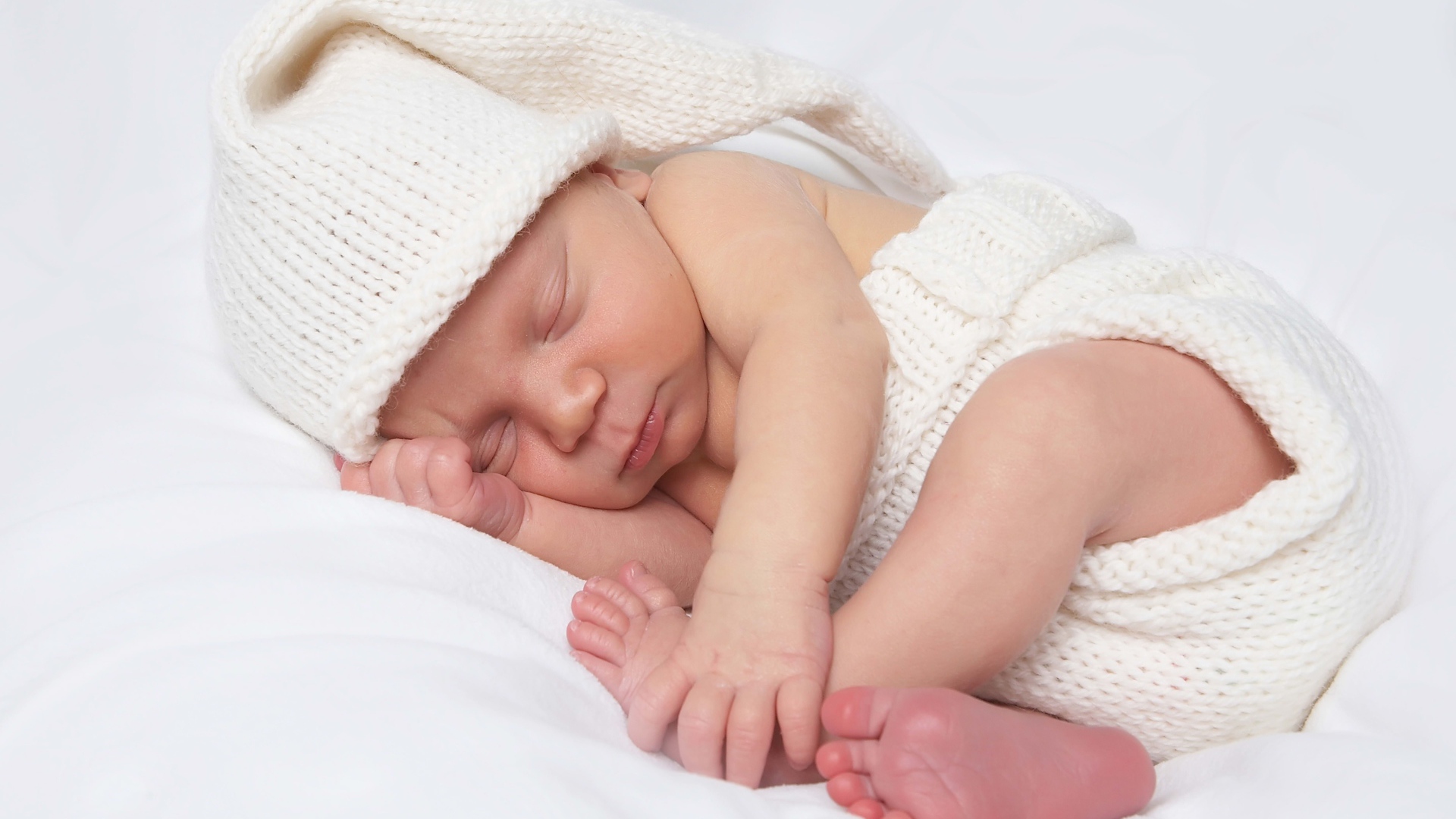 Нежный новорожденный ребенок в белом костюме