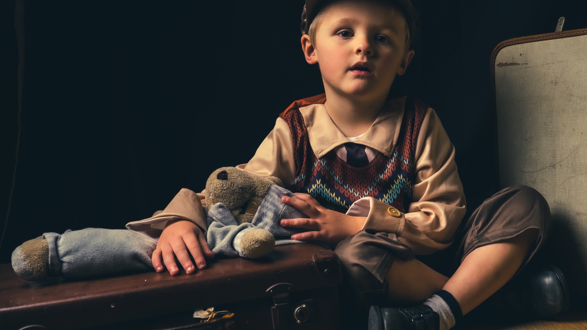 Маленький мальчик с чемоданом и игрушкой