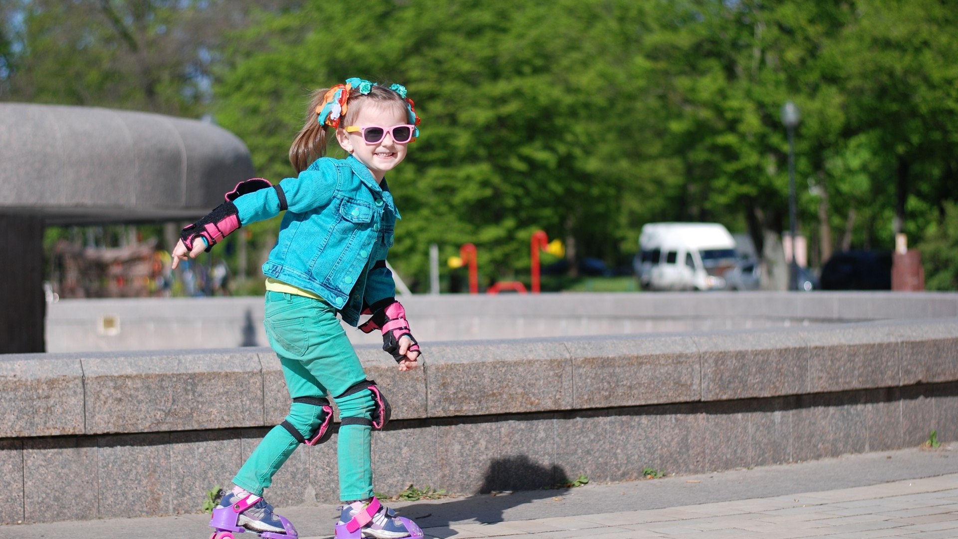 Маленькая веселая девочка катается на роликах