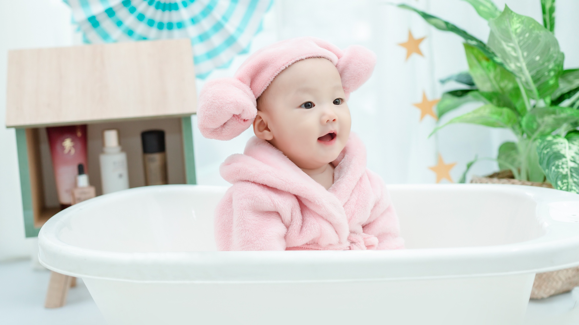 Маленький ребенок в розовом халате сидит в белой ванной