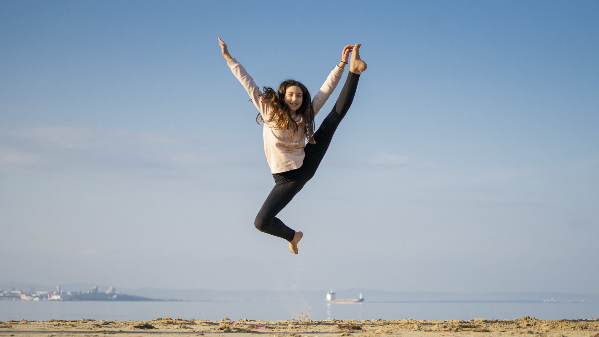 Маленькая девочка гимнастка на песке