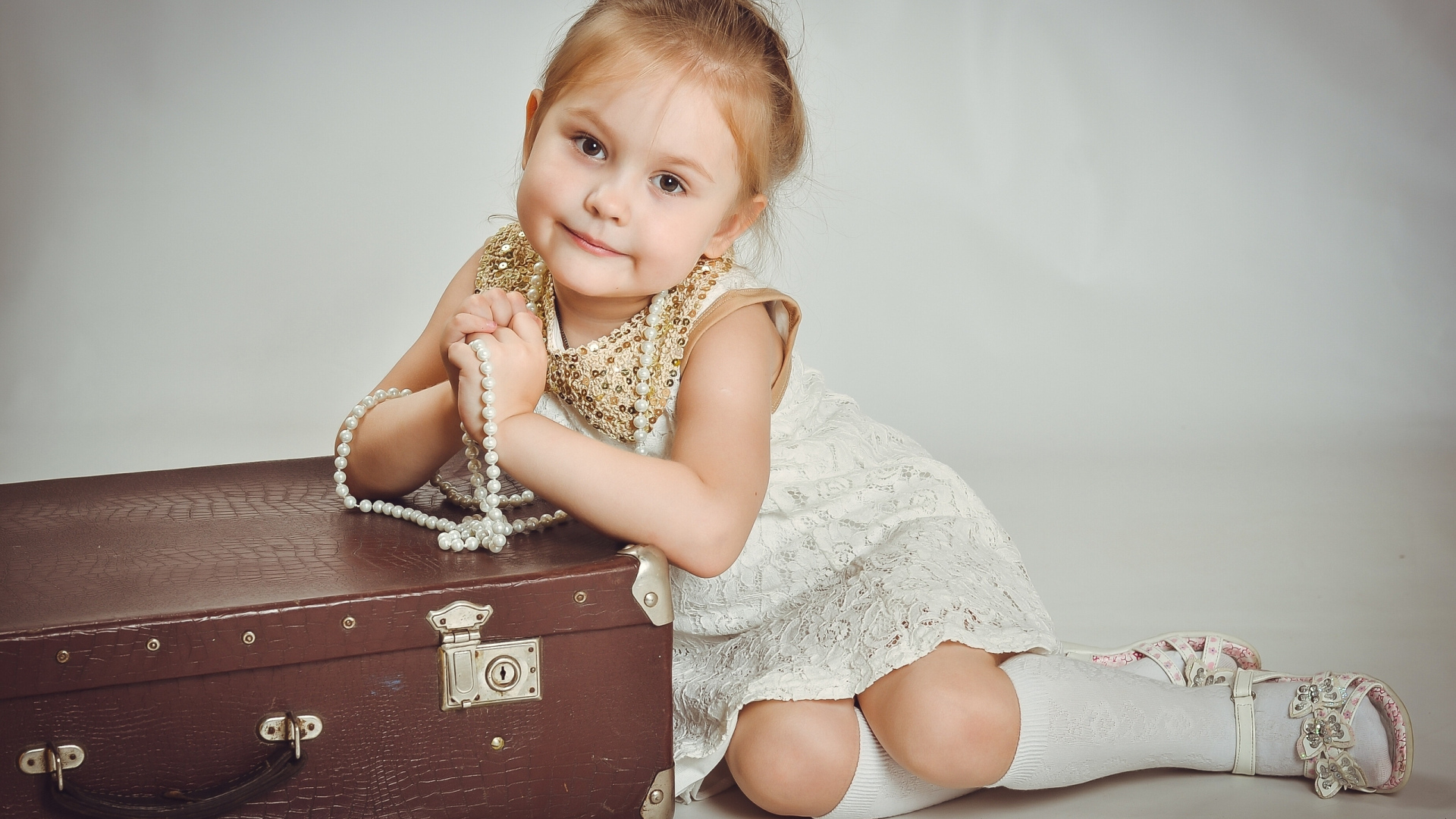Маленькая девочка в белом платье с чемоданом