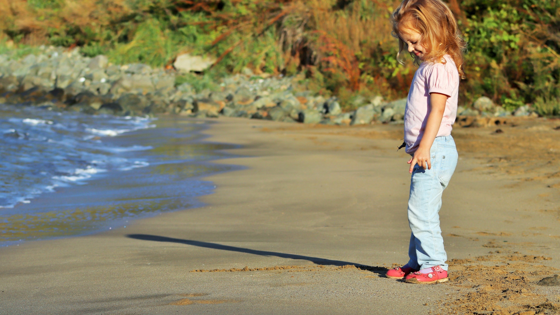 Маленькая девочка гуляет по мокрому песку 