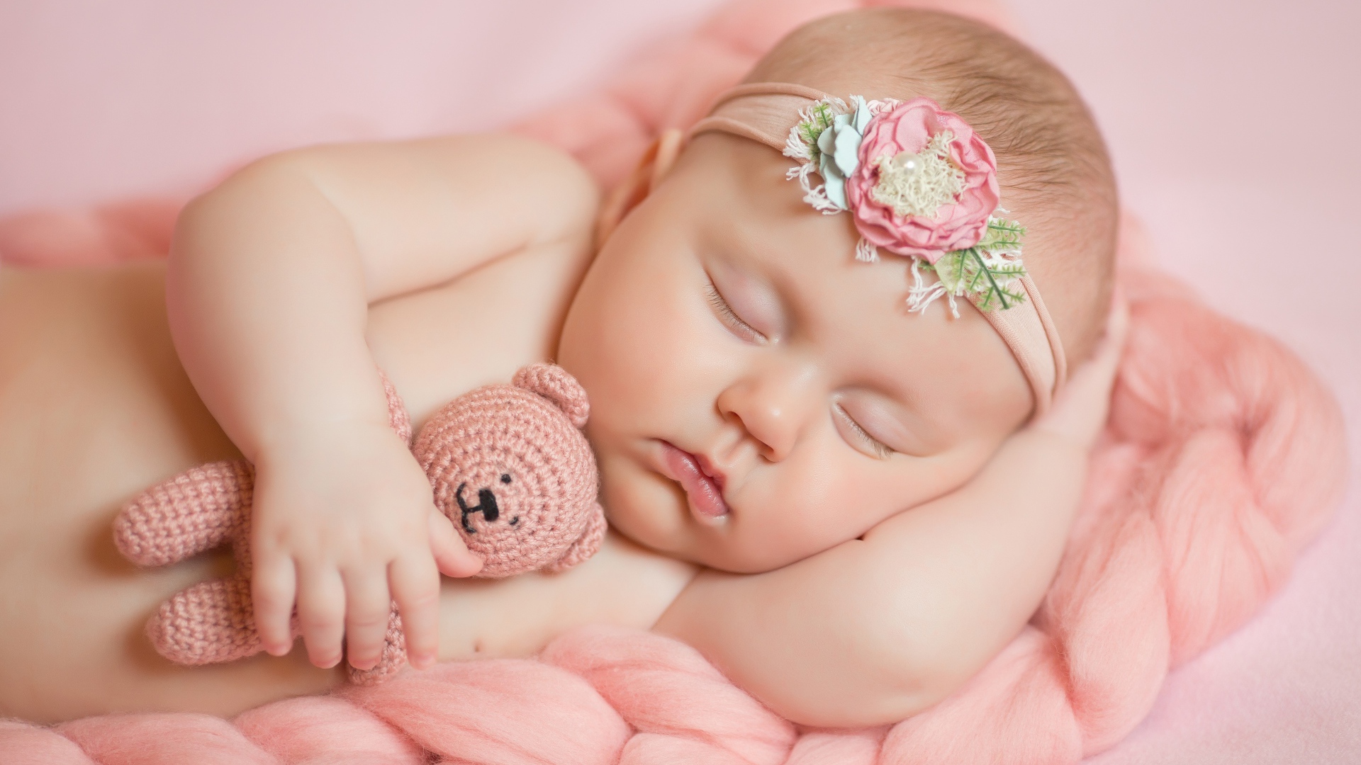 Маленькая новорожденная девочка с вязаным мишкой 