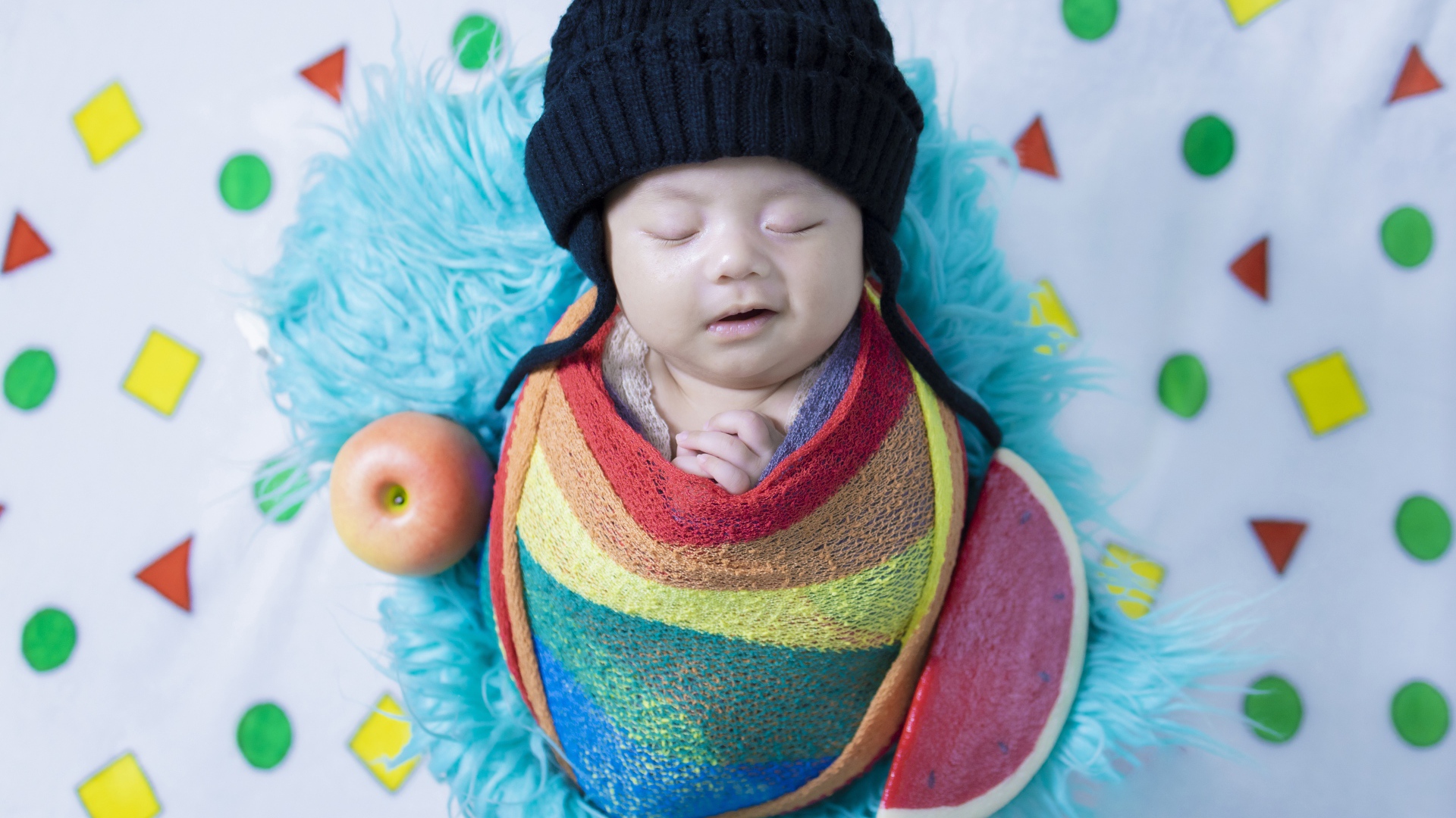 Маленький спящий ребенок в черной шапке 