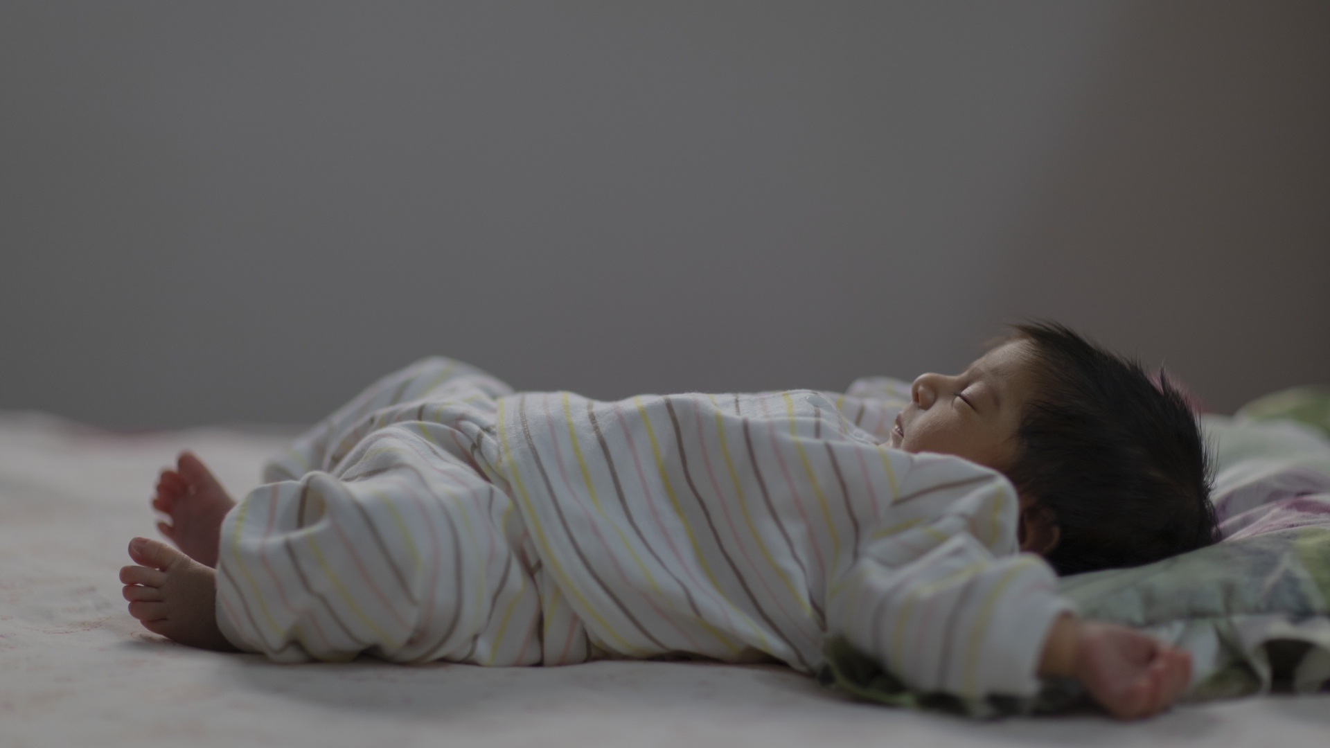 Маленький спящий грудной ребенок на кровати 