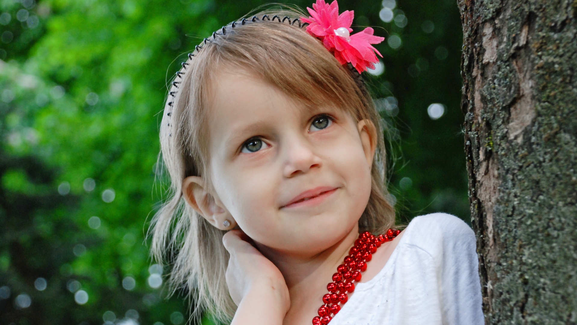 Маленькая улыбающаяся девочка у дерева 