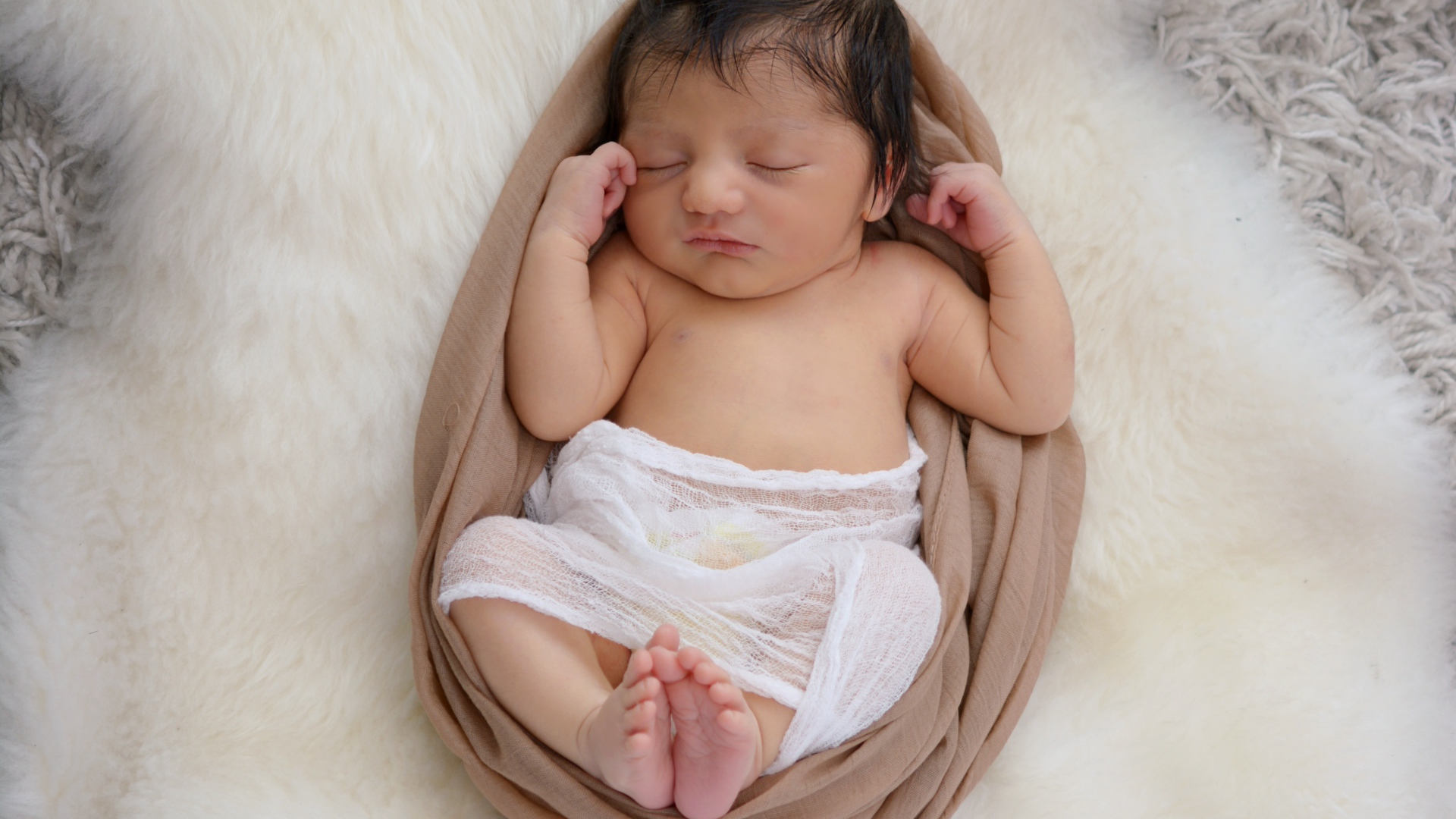 Спящий грудной ребенок на меховом покрывале 