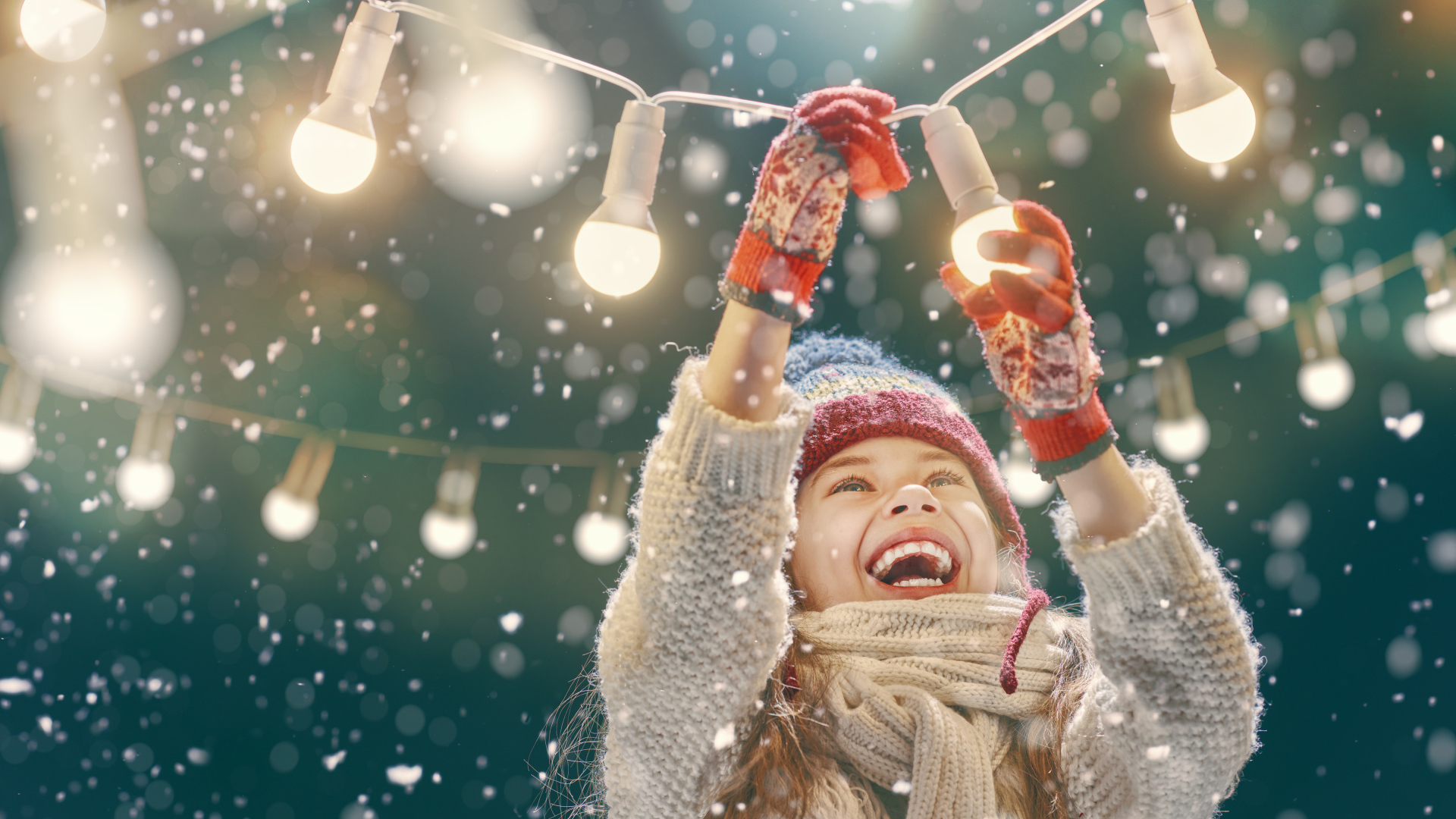 Улыбающаяся девочка вешает лампочки 