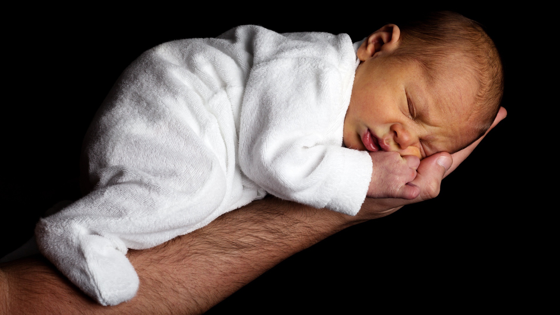Грудной ребенок спит на руке у папы