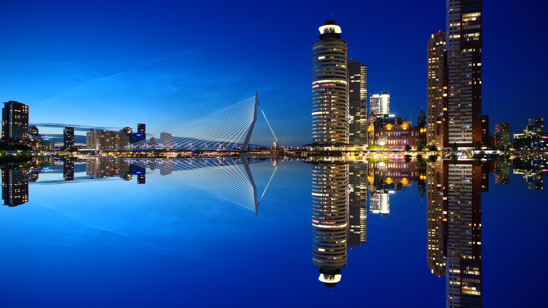 Небоскребы и мост отражаются в тихой воде