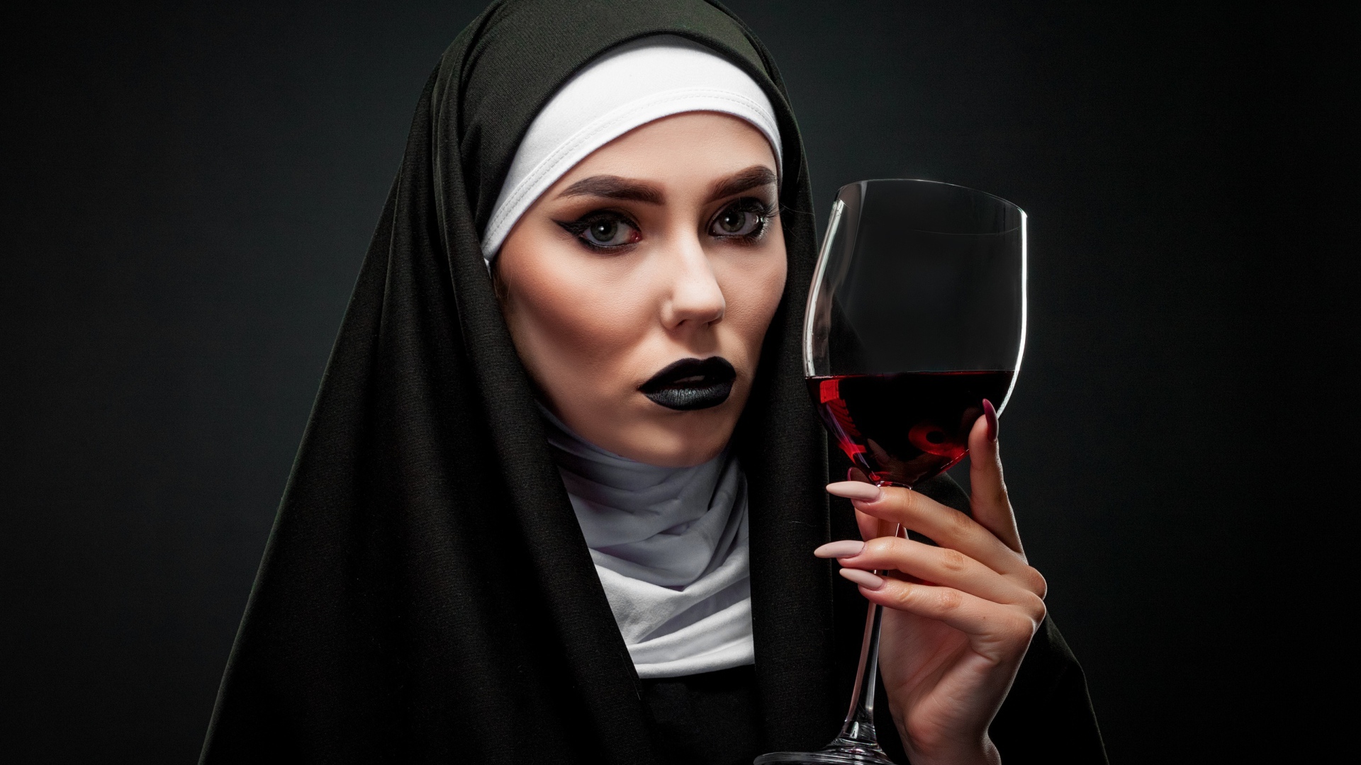 Девушка в костюме монашки с бокалом в руке