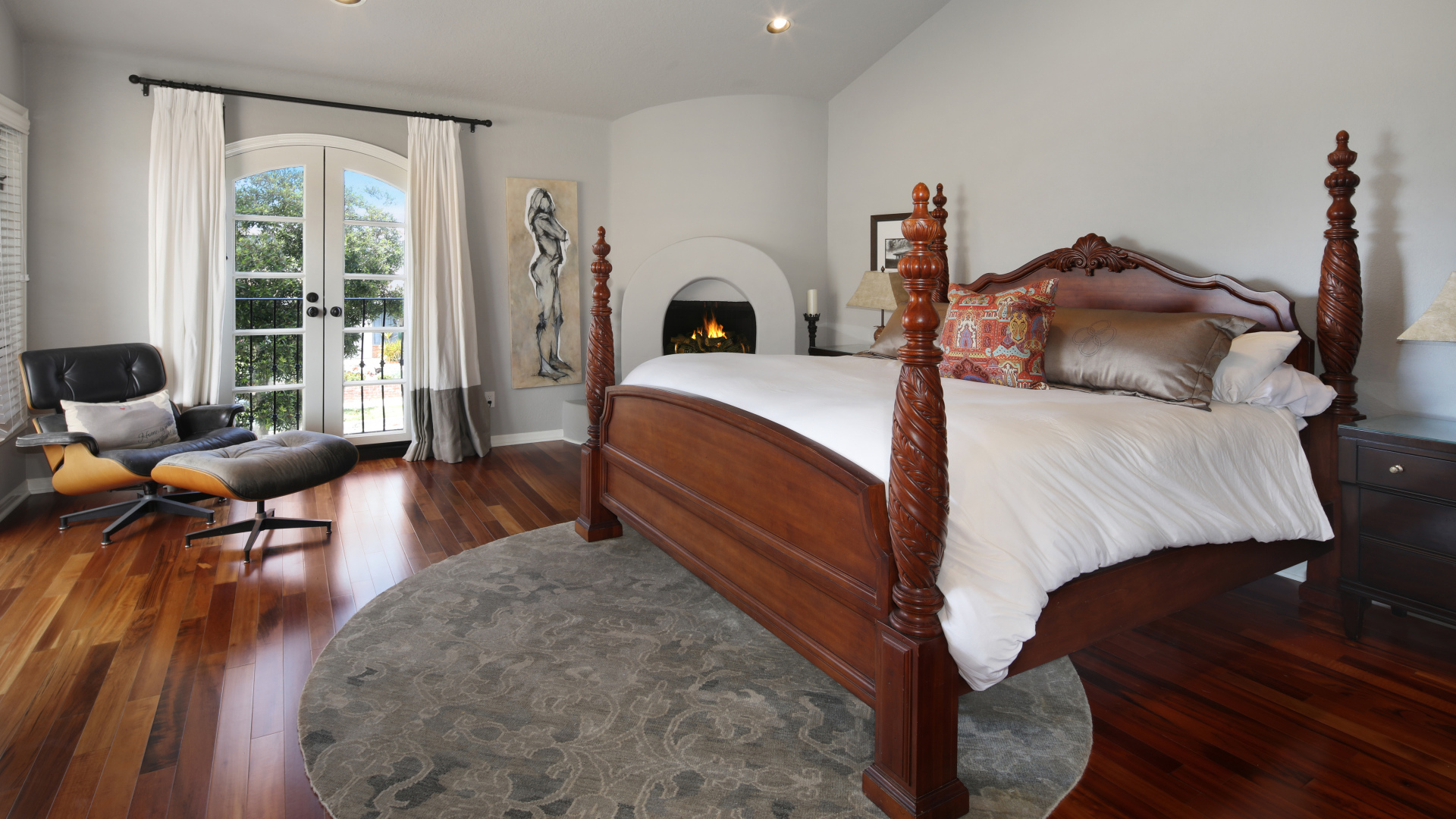 Большая деревянная кровать в спальне с камином 