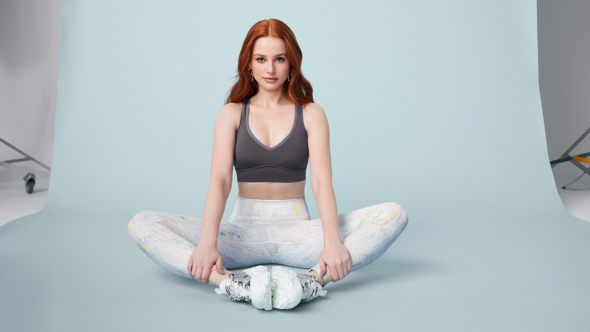 Рыжеволосая американская актриса Мэделин Петш сидит в позе лотоса