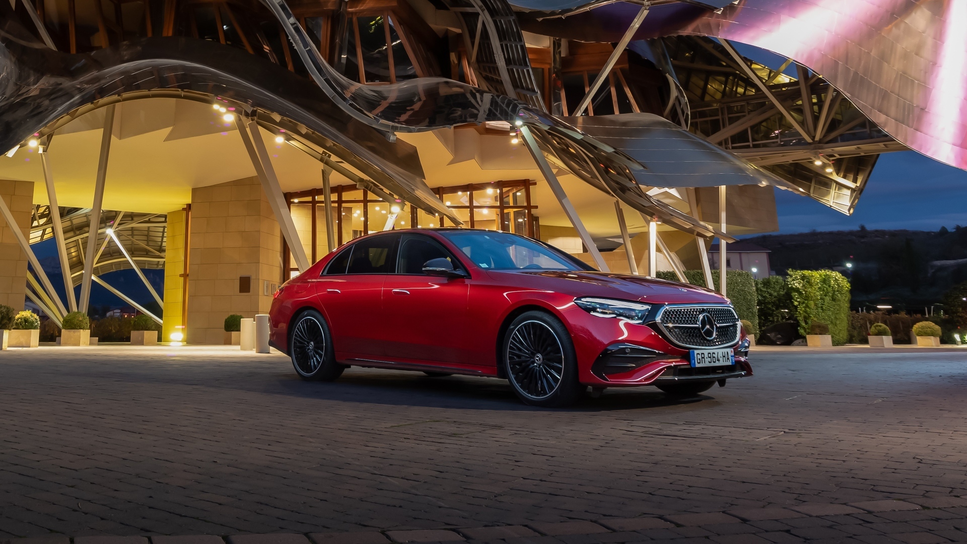 Красный автомобиль Mercedes-Benz E 220 D AMG Line у здания