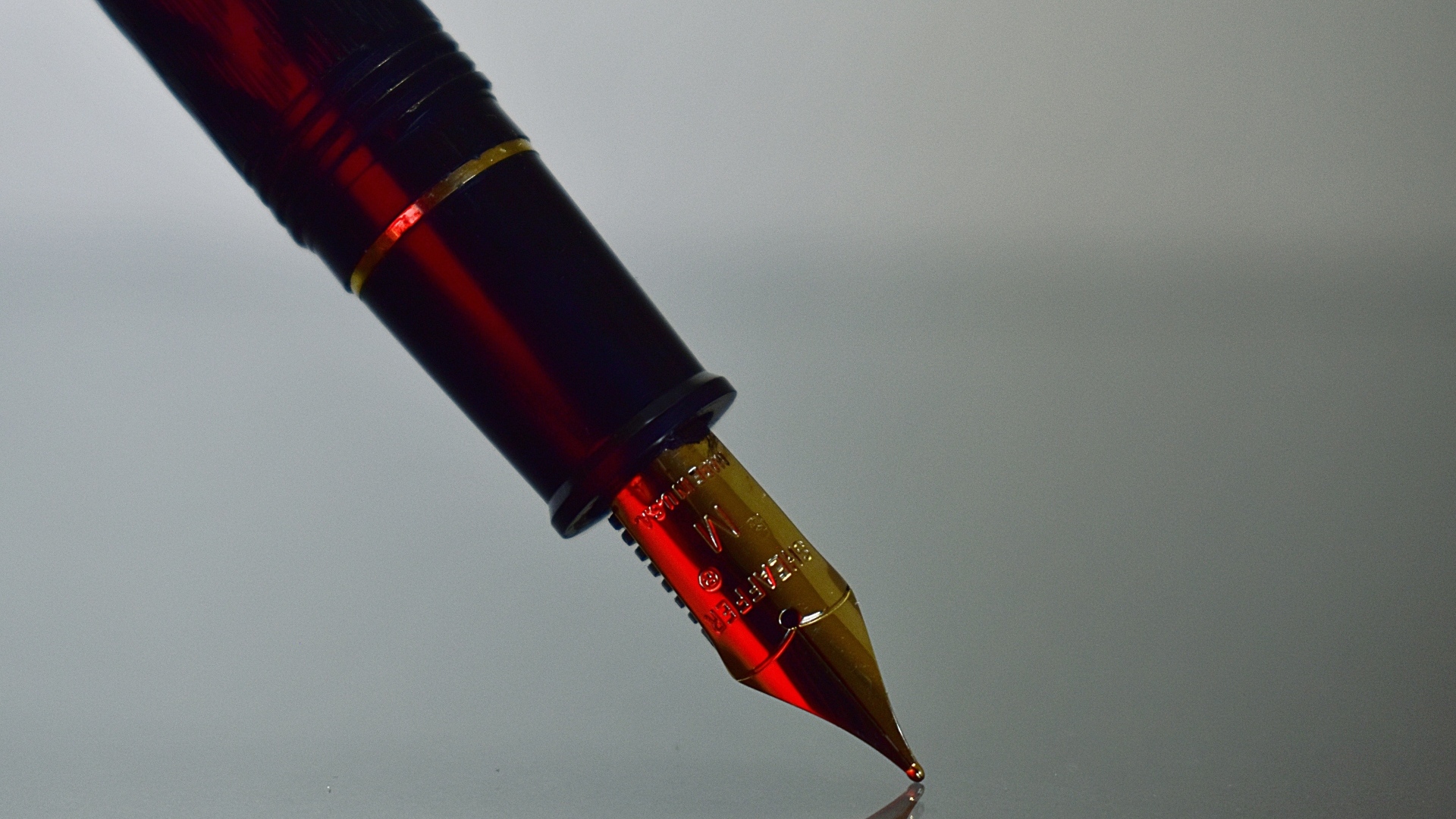 Золотое перо чернильной ручки на сером фоне