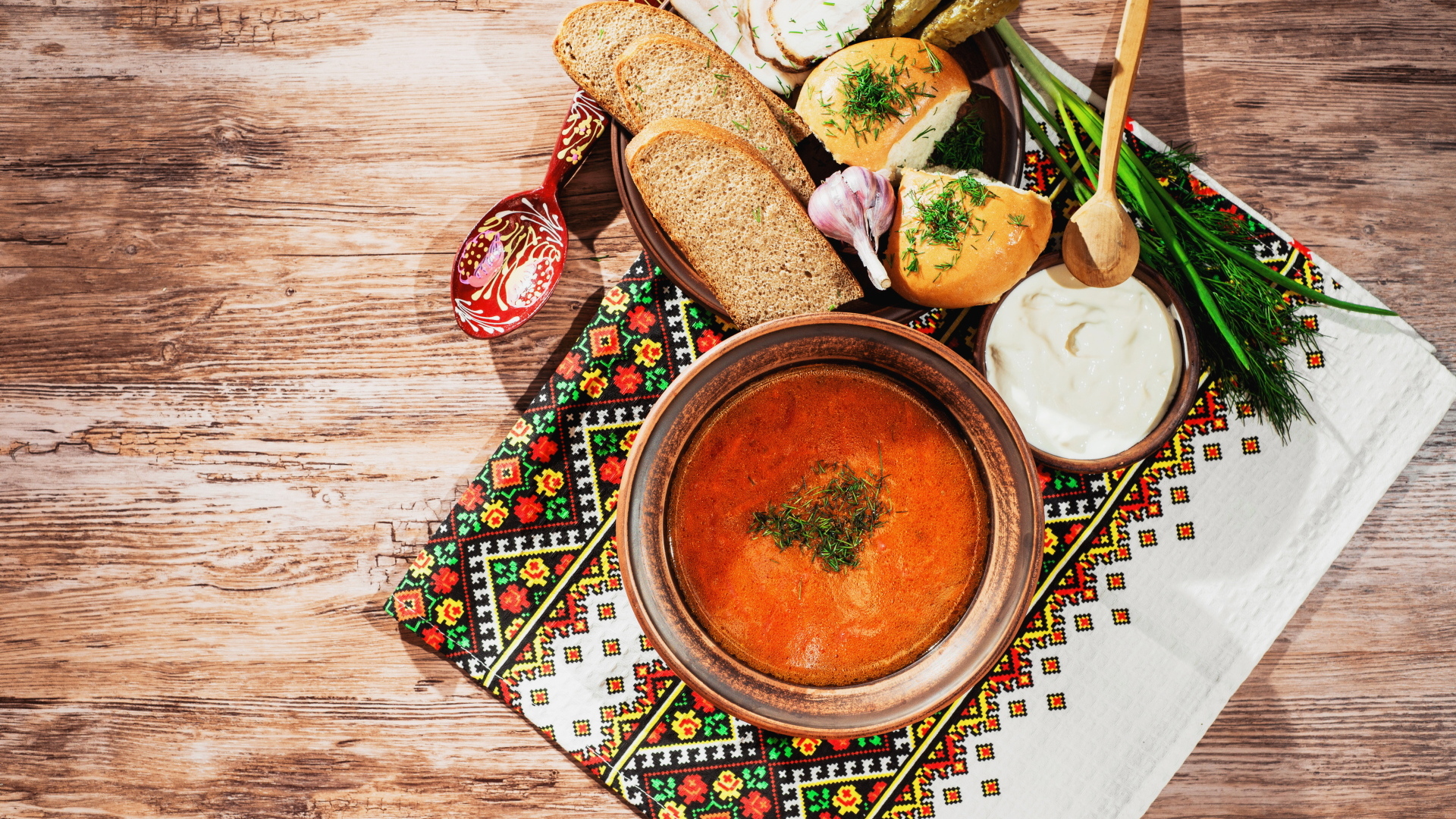 Тарелка борща на столе с салом, хлебом и зеленью